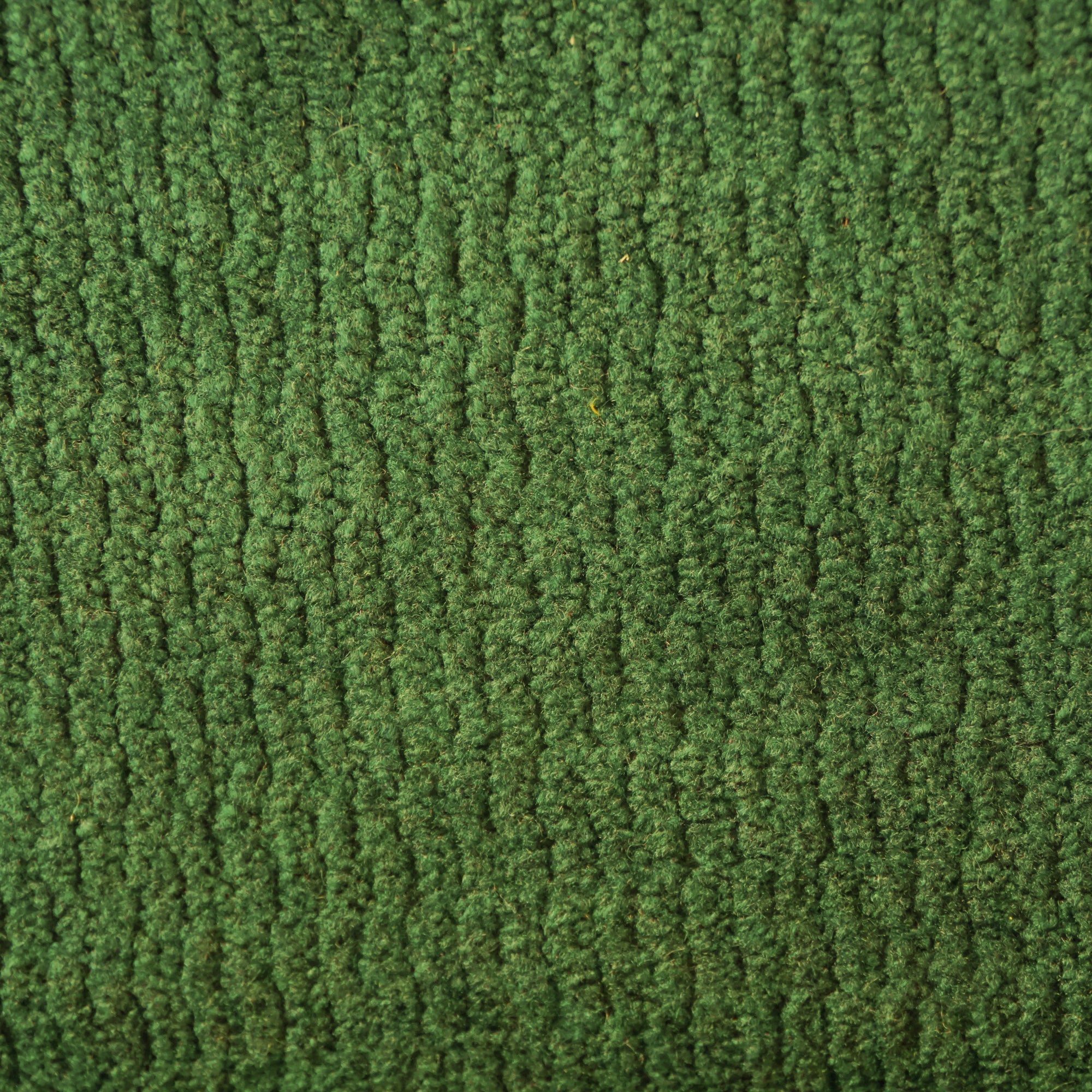 Primo piano del tappeto Personalizzazione in T32 di Divani.Store, caratterizzato da un ricco colore verde erba con un motivo a coste e una superficie morbida e fibrosa per una maggiore profondità.