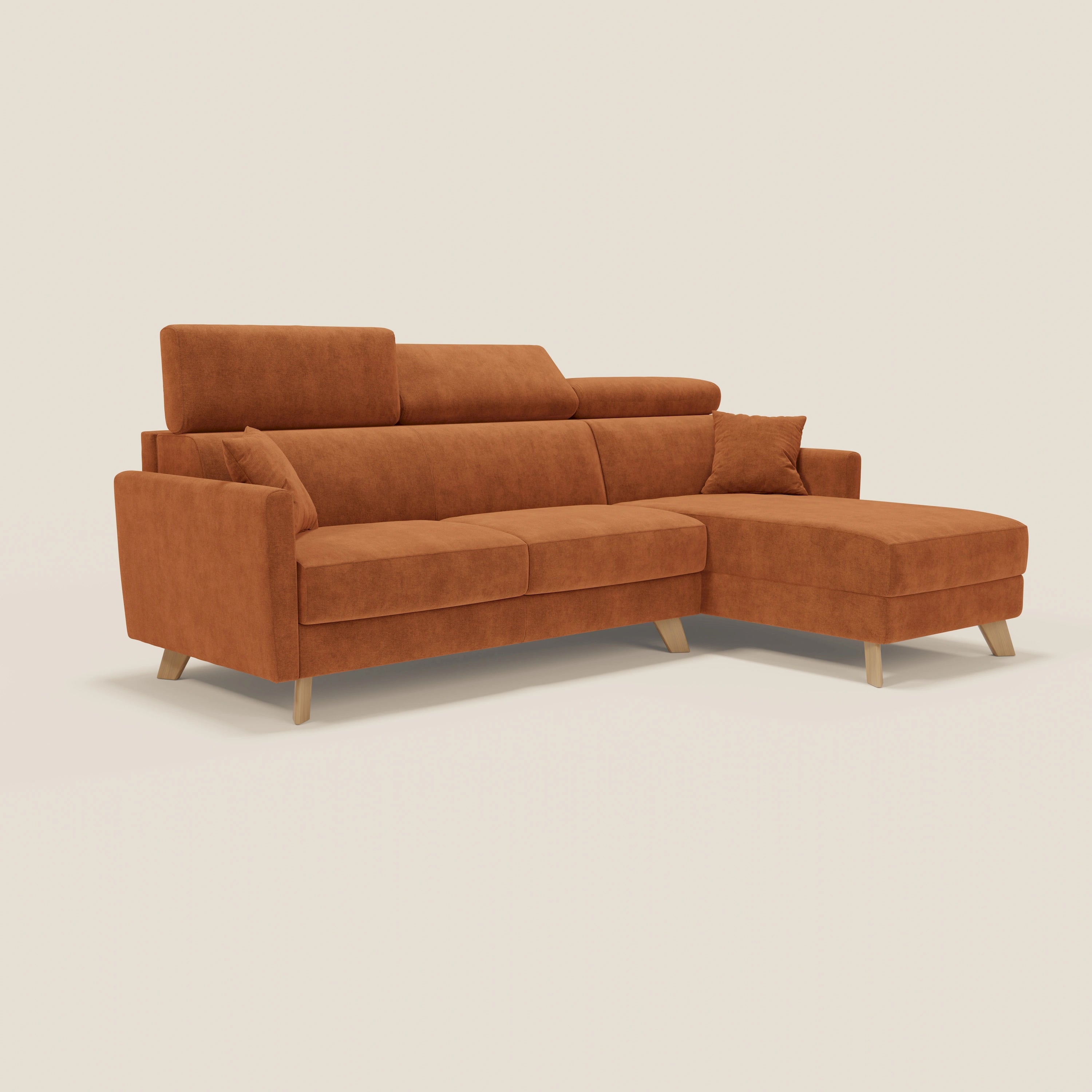 Il divano letto angolare Francy di Divani.Store è caratterizzato da un tessuto T17 arancione antimacchia, è sfoderabile, è dotato di una chaise longue destra, di un poggiatesta regolabile e di un cuscino d'accento, il tutto su un semplice sfondo bianco sporco.