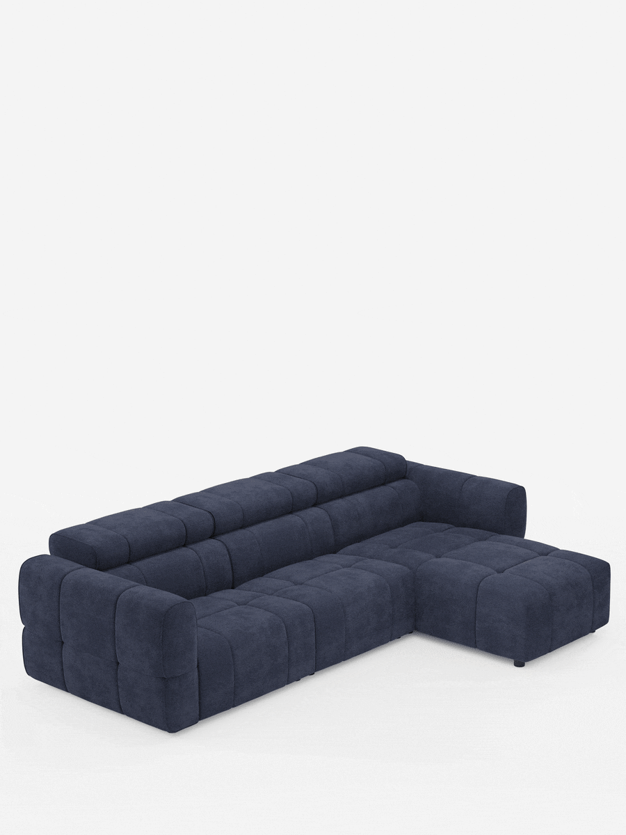 Un divano angolare modulare Giotto da 5 posti, 296 cm, in blu navy scuro, con penisola e funzione relax elettrica opzionale, rivestito in tessuto antimacchia T23, caratterizzato da un design con trapuntatura a griglia e braccioli bassi e squadrati, spicca su uno sfondo bianco a tinta unita.