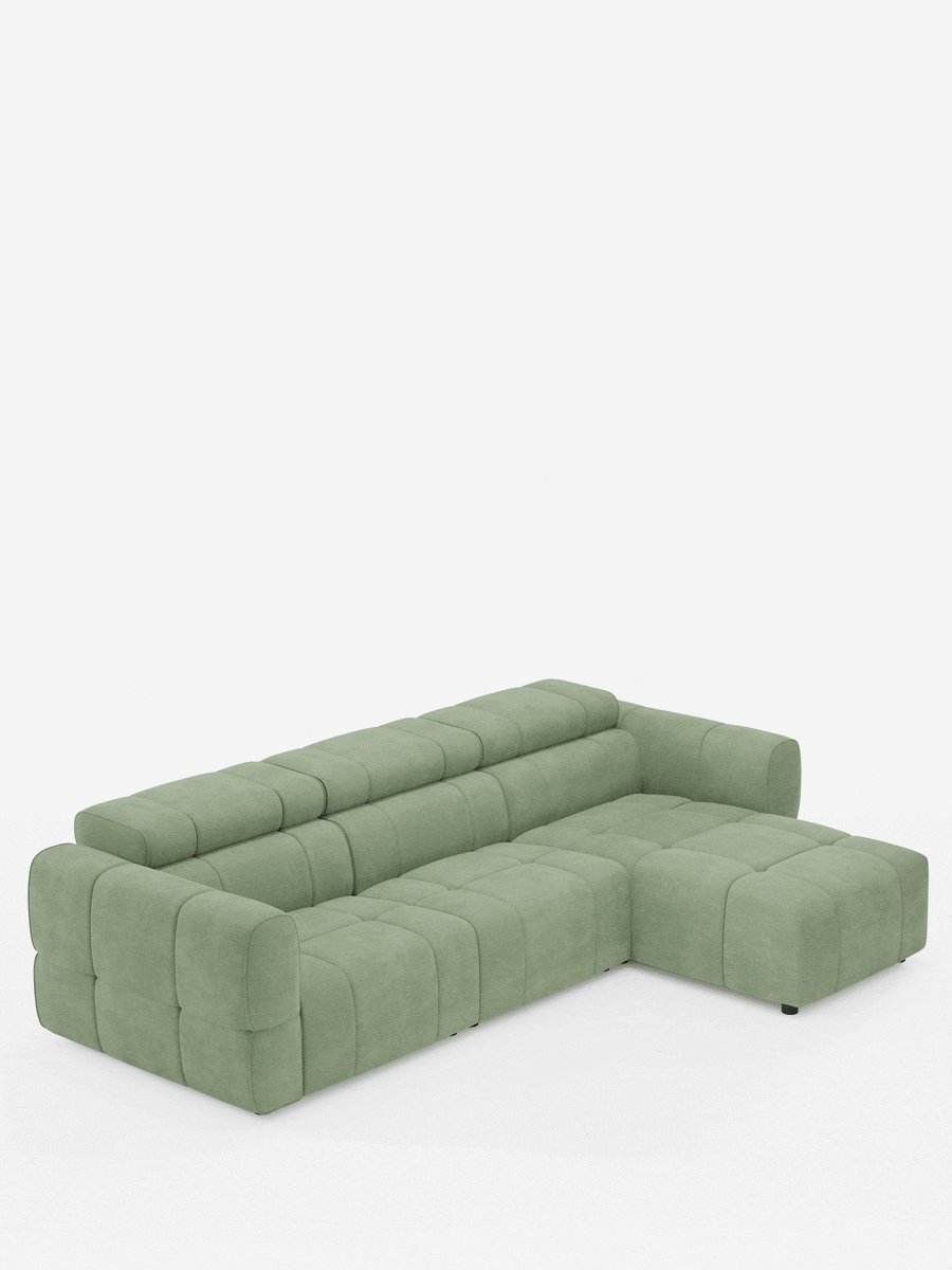 Un divano angolare modulare Giotto a 5 posti da 296 cm in verde salvia, con penisola e funzione relax elettrica opzionale, rivestito in tessuto antimacchia T23, caratterizzato da un design a griglia trapuntata dal profilo basso su uno sfondo bianco a tinta unita.