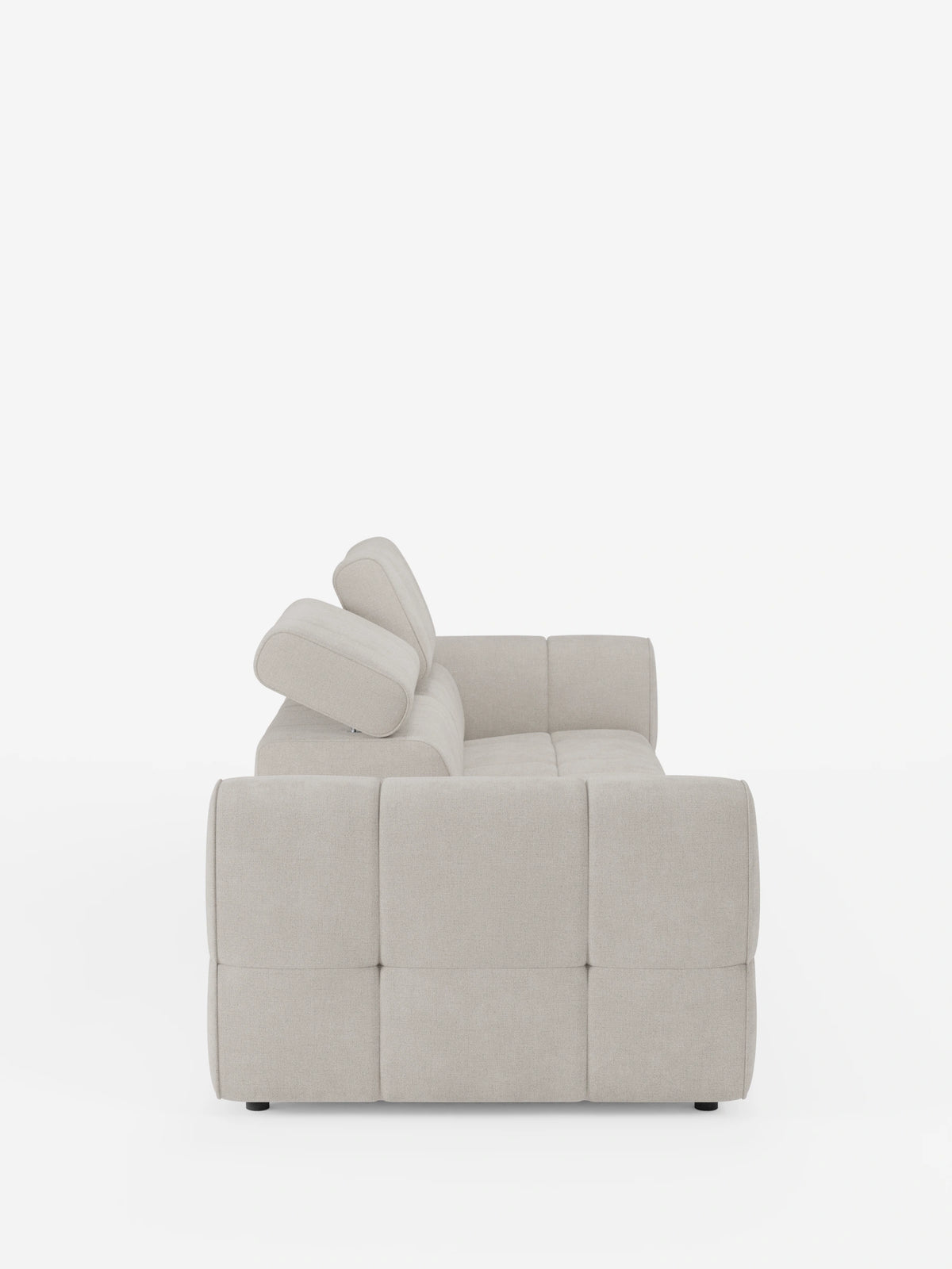 Una vista laterale del divano componibile Giotto con terminale aperto – opzione relax elettrico in tessuto smacchiabile T23 beige, un divano modulare con seduta trapuntata, due poggiatesta regolabili e piedini bassi e scuri su sfondo bianco.