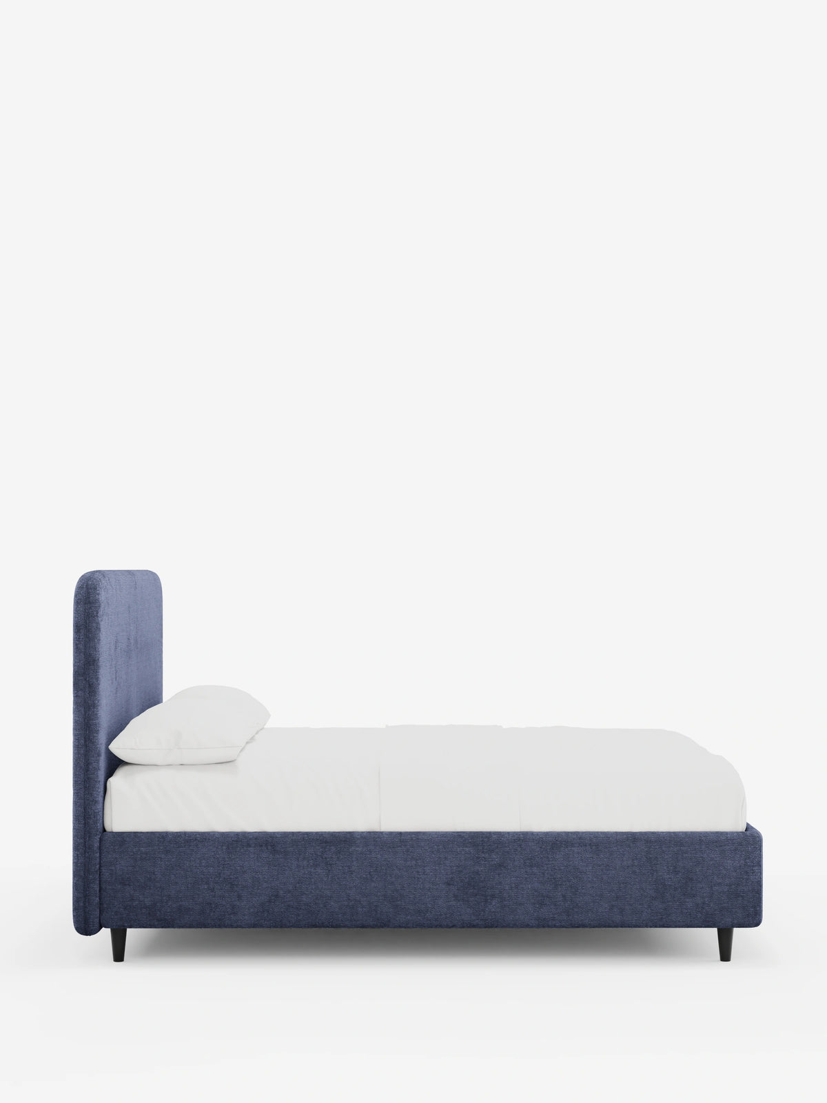 Vista laterale di un letto KAELOS minimal imbottito di colore blu scuro, caratterizzato da una testiera arrotondata, biancheria da letto bianca con un cuscino e sottili gambe nere su uno sfondo bianco a tinta unita.