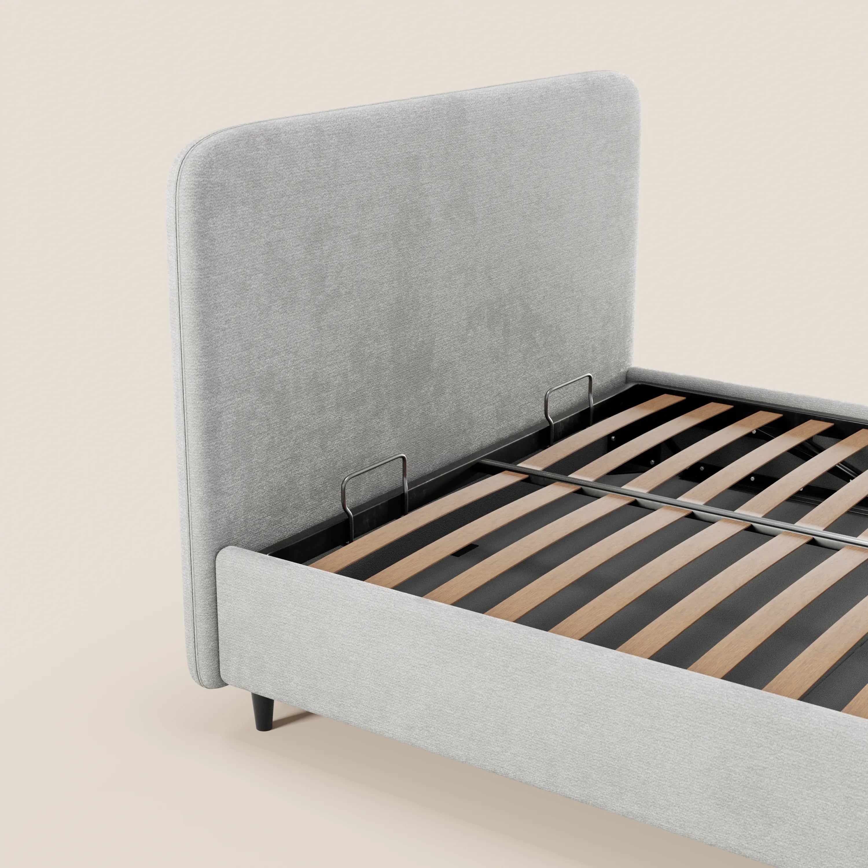 Il letto imbottito KAELOS minimal di Letti.store presenta una testiera alta e arrotondata in ciniglia grigio chiaro, gambe alte, doghe in legno, supporti in metallo nero e vano contenitore. Nell’immagine è raffigurato senza materasso su uno sfondo beige chiaro a tinta unita.