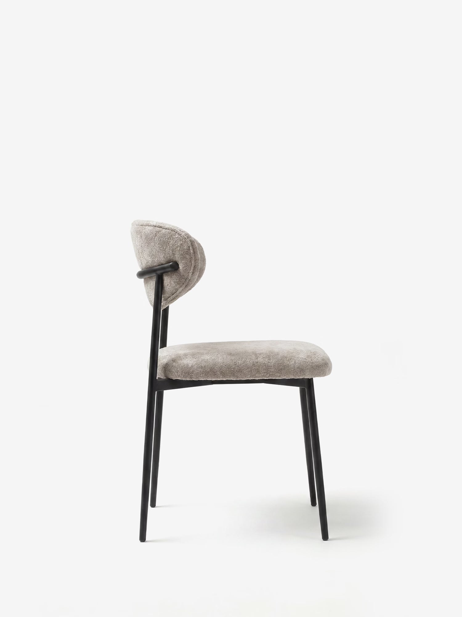 Luce, poltrona imbottita in morbido tessuto ciniglia di Divani.Store: seduta grigio chiaro e schienale curvo, struttura minimalista con gambe sottili in metallo nero, vista laterale su sfondo bianco.