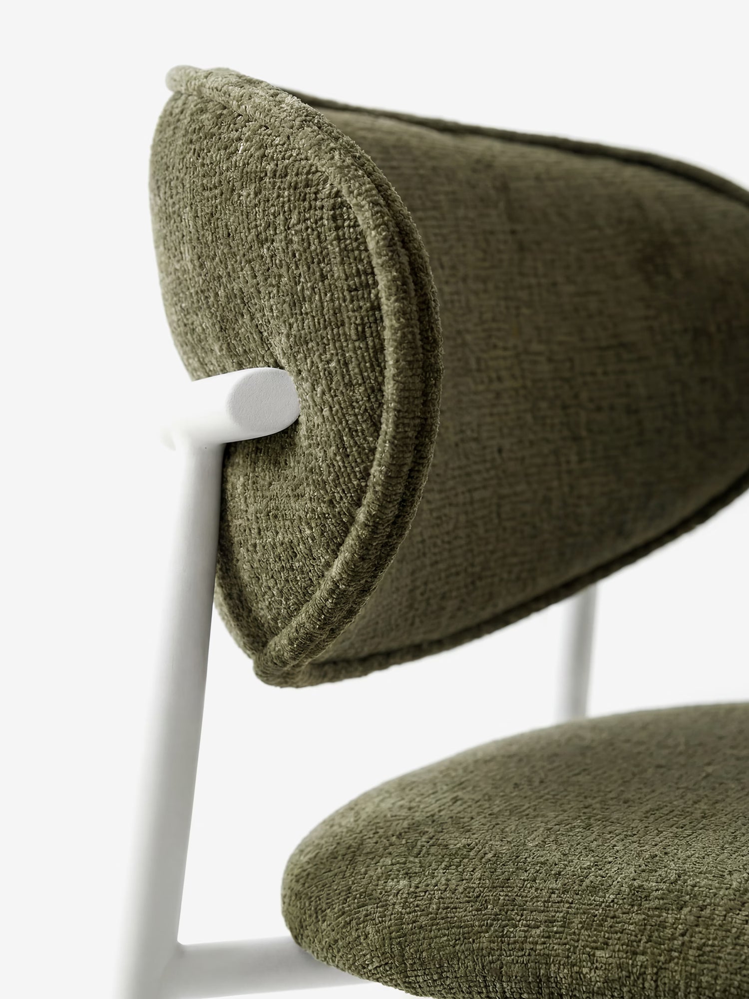 Primo piano della Luce Sedia imbottita di Divani.Store, caratterizzata da uno schienale curvo imbottito in tessuto ciniglia verde oliva e da una struttura minimalista in metallo bianco dalle linee geometriche slanciate su sfondo bianco.
