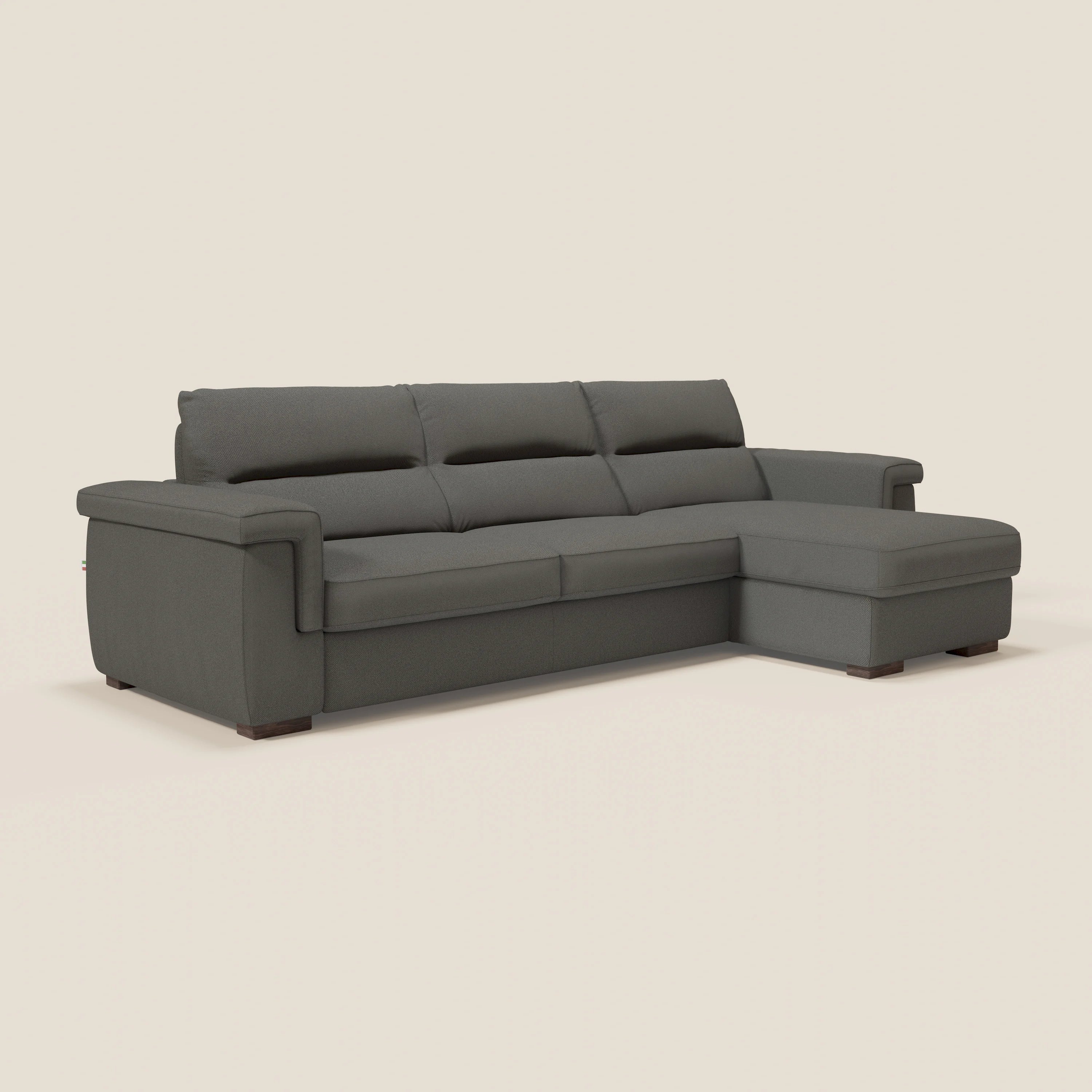 Il divano letto angolare Magnolia con Penisola Contenitore di Divani.Store, in tessuto smacchiabile antracite T05 e materasso H18 cm, offre Comfort Profondo su uno sfondo beige chiaro.