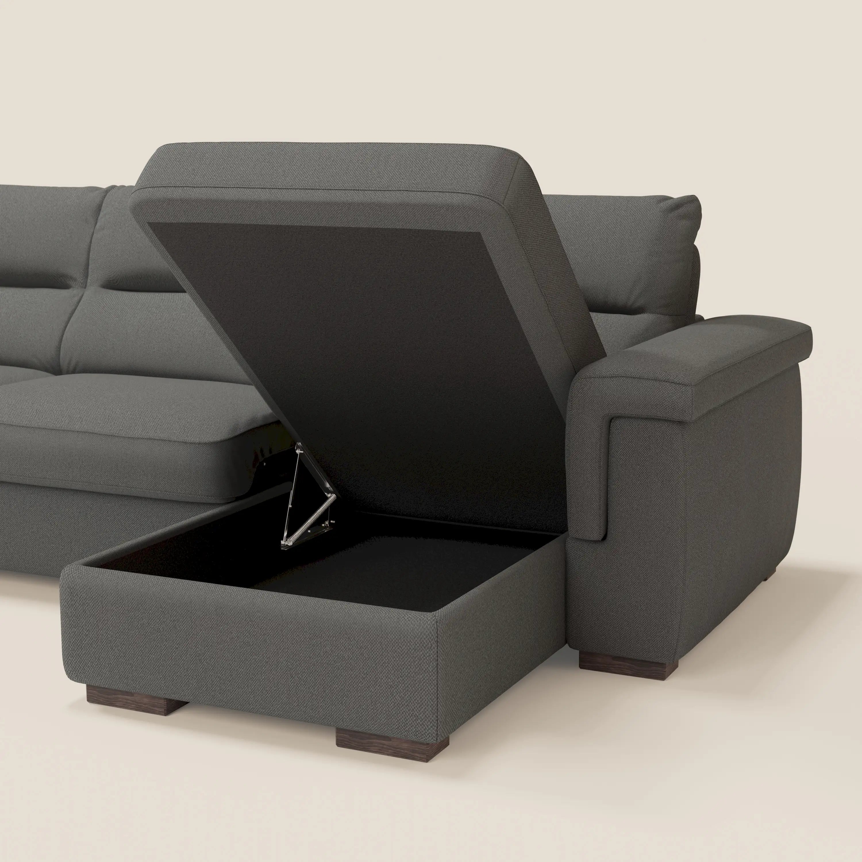 Il divano letto angolare Magnolia con Penisola Contenitore di Divani.Store in smacchiabile T05 antracite è caratterizzato da una poltrona contenitore nascosta, cuscini di schienale trapuntati, ampi braccioli e gambe corte in legno, su sfondo chiaro.