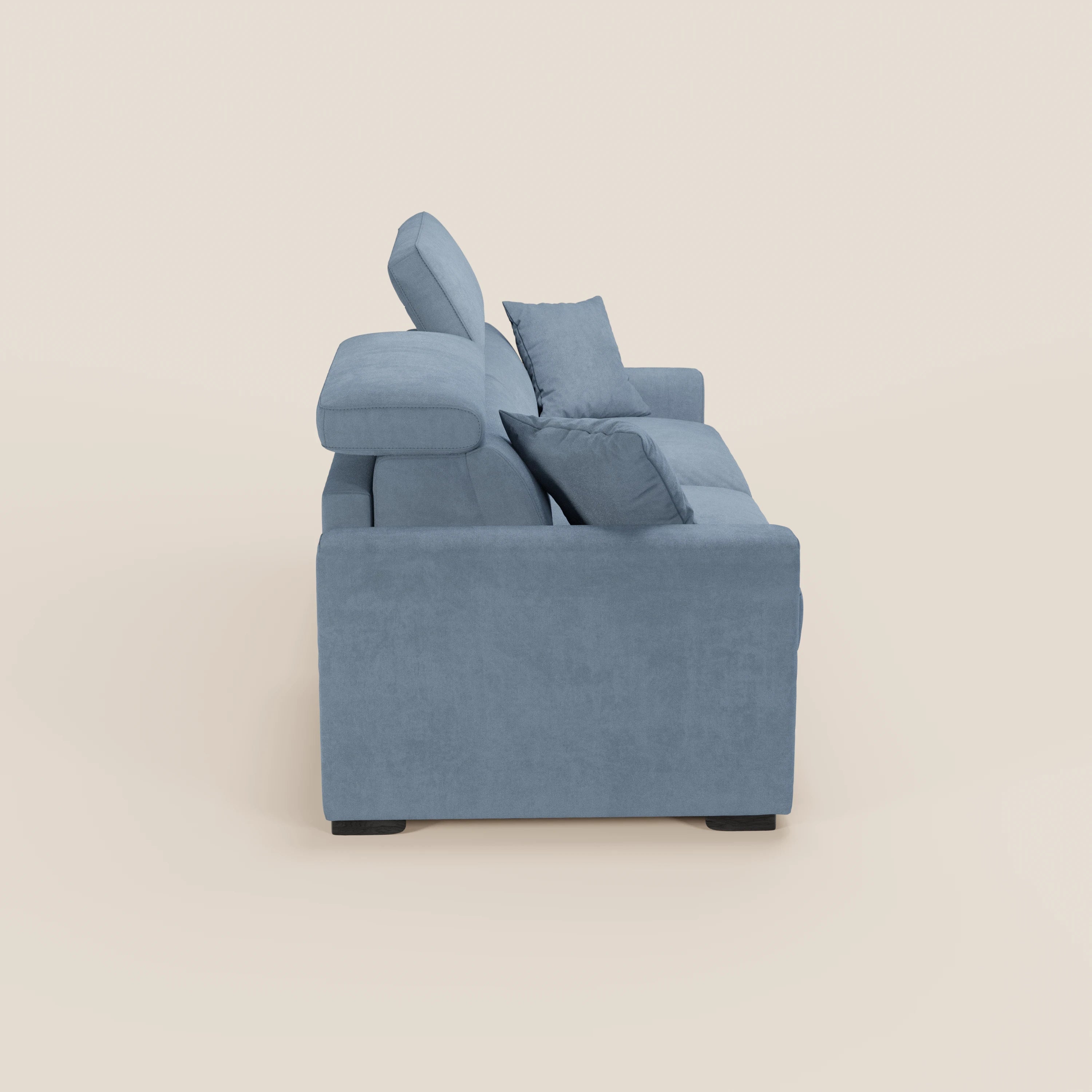 Vista laterale del divano letto a 3 posti Maximus con materasso ALTO 20 cm di Divani.Store, color azzurro chiaro, con cuscini spessi, due cuscini decorativi, poggiatesta reclinabile, piedini neri corti e schienali imbottiti che superano l'altezza dei braccioli, su uno sfondo bianco sporco.