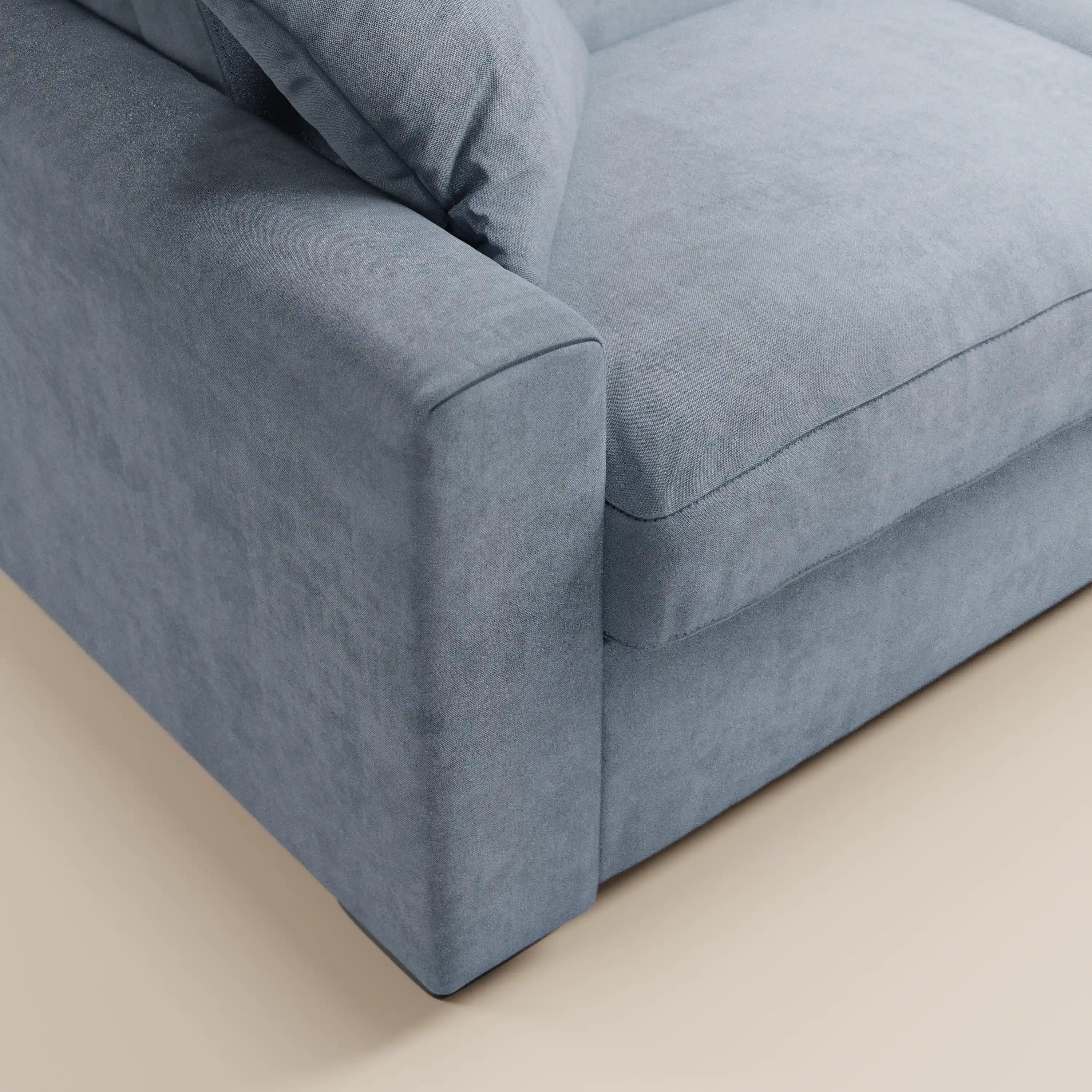 Primo piano del divano letto Maximus a 3 posti con materasso ALTO 20 cm di Divani.Store, realizzato in un moderno tessuto grigio chiaro, smacchiabile e certificato Oeko-Tex, che mette in risalto i braccioli, i cuscini e la seduta su uno sfondo di pavimento beige chiaro. Questo divano si caratterizza per le linee pulite e dritte, l’aspetto morbido e lussuoso e i poggiatesta reclinabili per un comfort ancora maggiore.