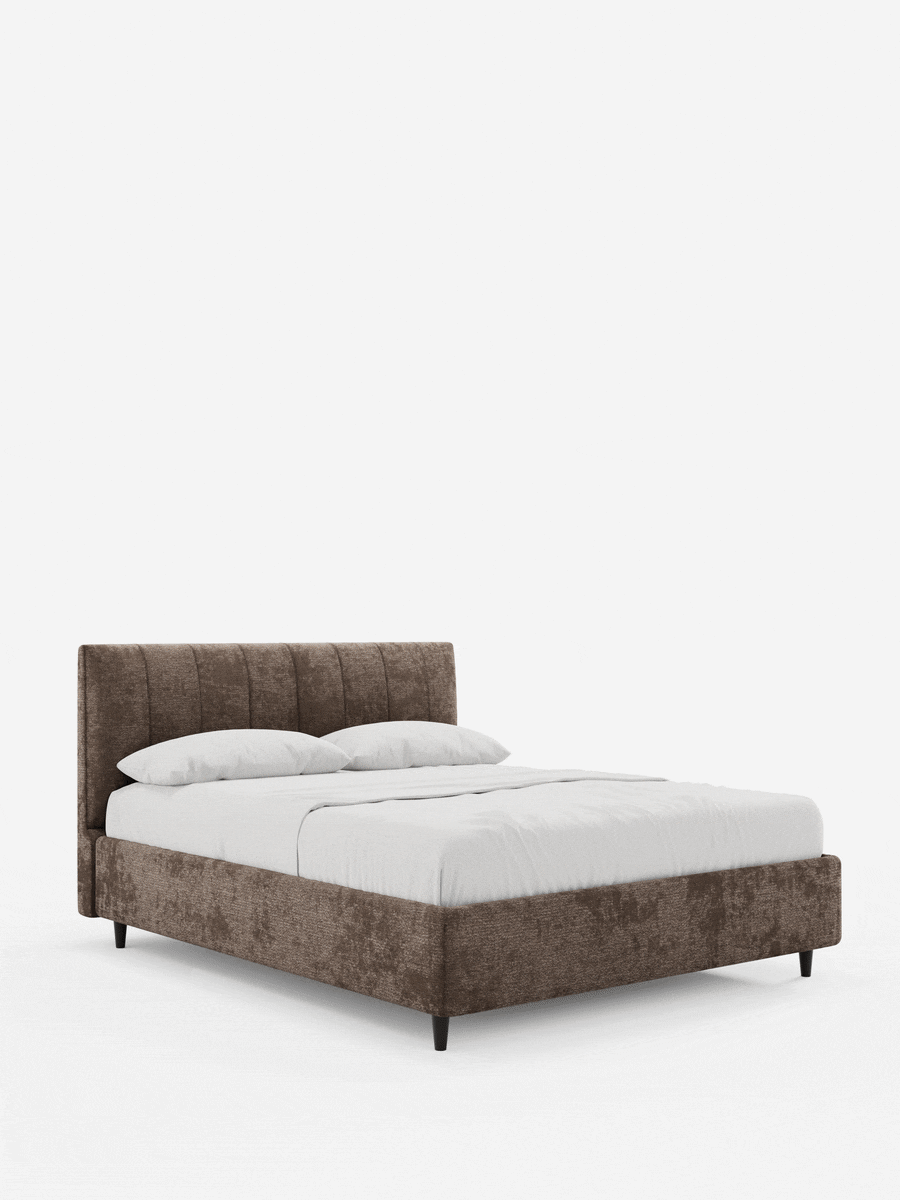 ONYX, letto imbottito con contenitore e testiera verticale in tessuto certificato Oeko-Tex®: un letto imbottito moderno di colore marrone con una testiera alta e cucita verticalmente, biancheria da letto di un bianco brillante e gambe sottili di colore scuro che risaltano su uno sfondo chiaro.