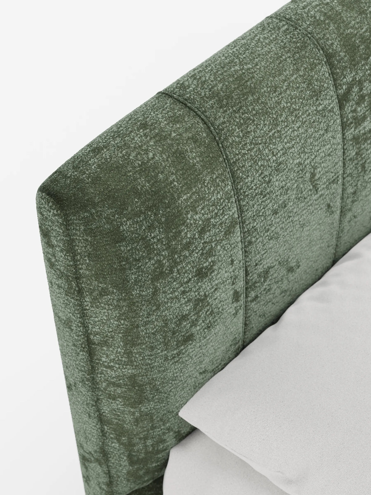 Un primo piano del letto imbottito ONYX color verde bosco, dotato di vano contenitore e testiera verticale in tessuto certificato Oeko-Tex®, caratterizzato da trapuntatura a canali verticali, tessuto opaco testurizzato e un cuscino grigio chiaro appoggiato all’angolo.