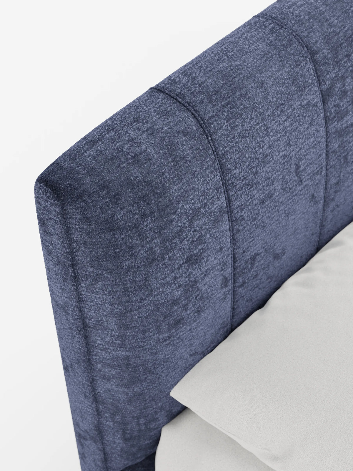 Un primo piano del letto imbottito ONYX con contenitore e testiera verticale in tessuto certificato Oeko-Tex®, caratterizzato da pannelli verticali blu intenso e un cuscino grigio chiaro su uno sfondo bianco a tinta unita.