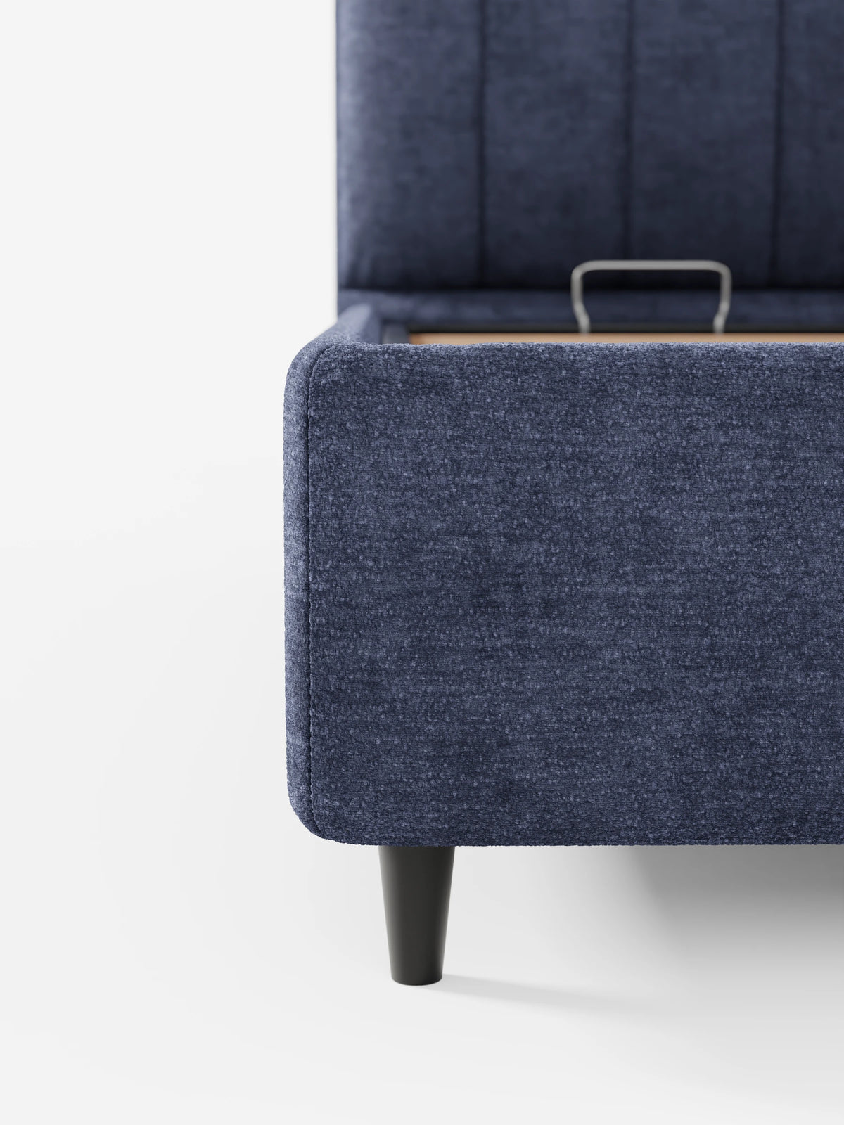 Letto imbottito ONYX con contenitore e testiera verticale in tessuto certificato Oeko-Tex® blu navy, caratterizzato da trapuntatura verticale, base del materasso rialzata e gambe affusolate scure su sfondo bianco.