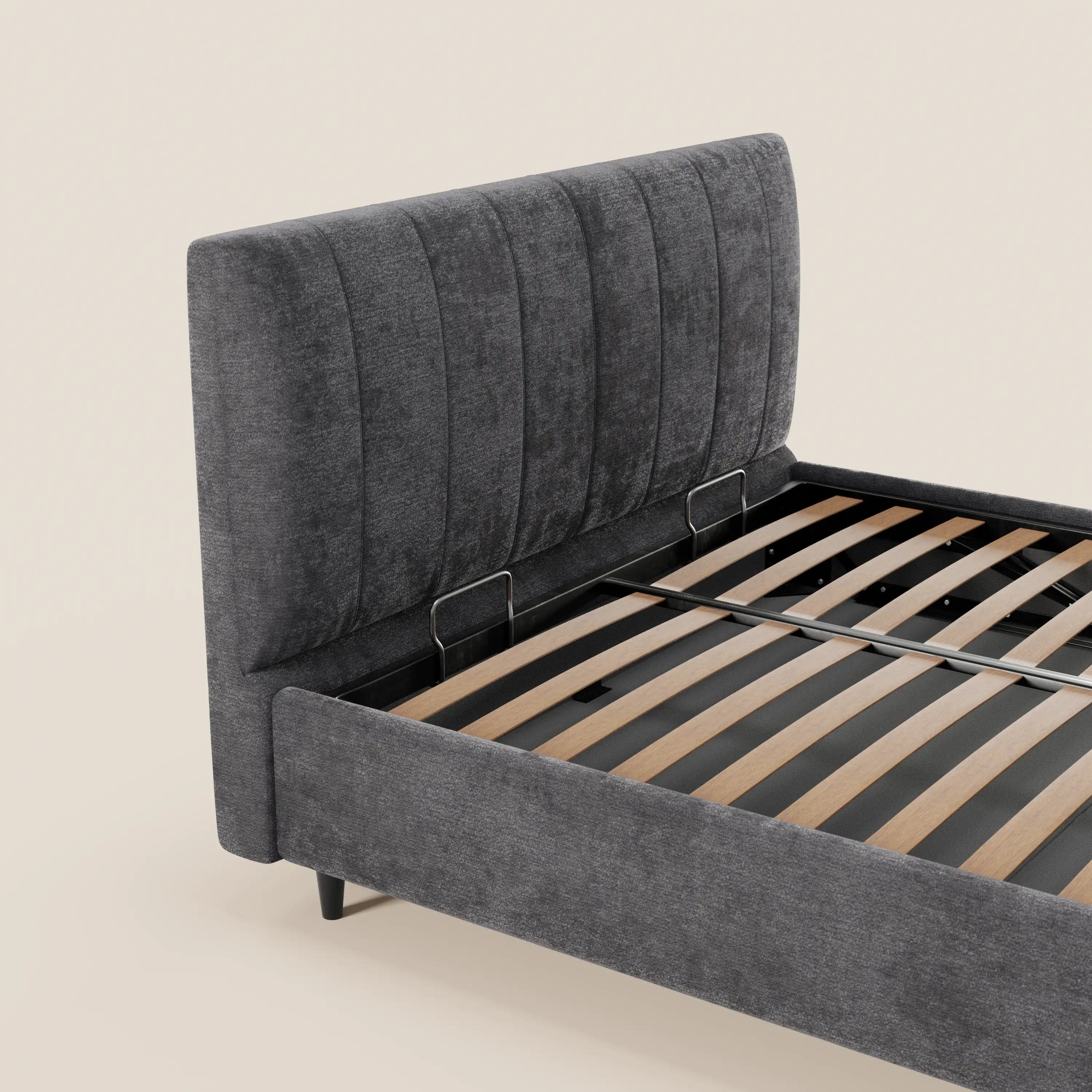Il letto imbottito ONYX di Letti.store presenta una testiera alta, imbottita e con cuciture verticali, certificata Oeko-Tex® in grigio antracite, una base contenitore, doghe in legno e gambe nere. Nell’immagine è raffigurato su sfondo beige; materasso e biancheria da letto non inclusi.