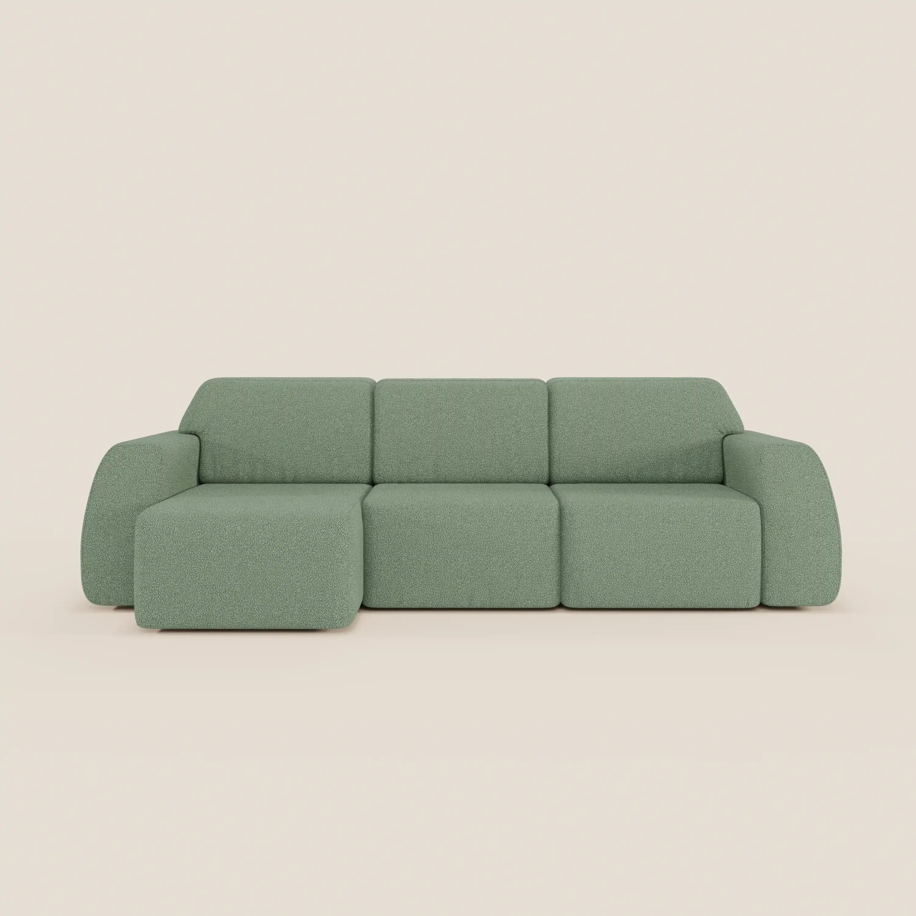 Il divano angolare Orbit di Divani.Store è caratterizzato da una chaise reversibile, sedute allungabili e tessuto antimacchia effetto cotone T33 in verde chiaro con cuscini spessi e braccioli arrotondati su sfondo beige.