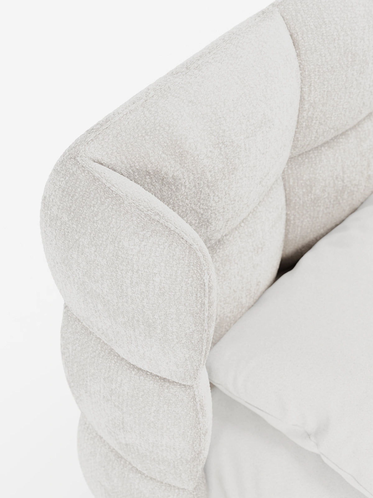 Un primo piano di un letto RAGNAR color crema, imbottito, con contenitore e testiera capitonné avvolgente, caratterizzato da un design imbottito e testurizzato, con pannelli arrotondati che si incurvano in avanti e morbida biancheria da letto bianca.