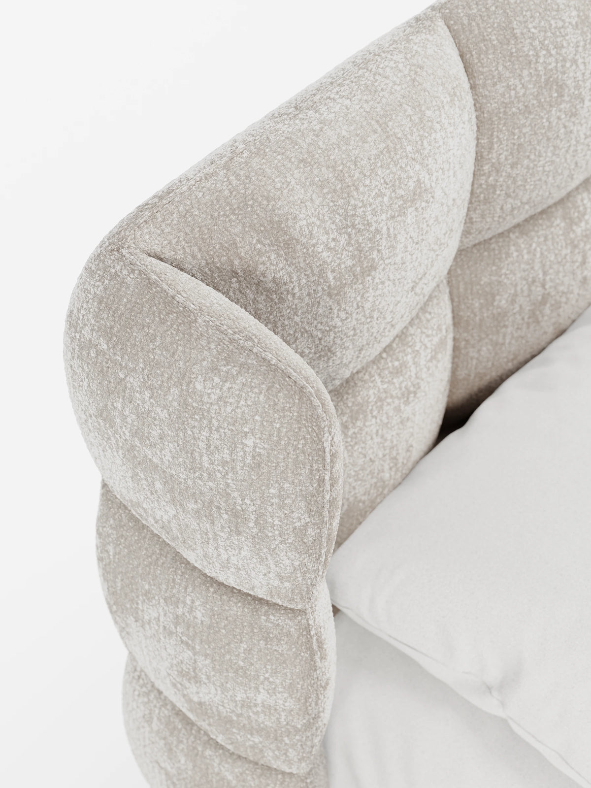 Un primo piano di un letto imbottito RAGNAR color beige chiaro con contenitore e testiera capitonné avvolgente, caratterizzata da ampi pannelli arrotondati dal design curvo in stile “wingback”, accanto a un cuscino bianco.