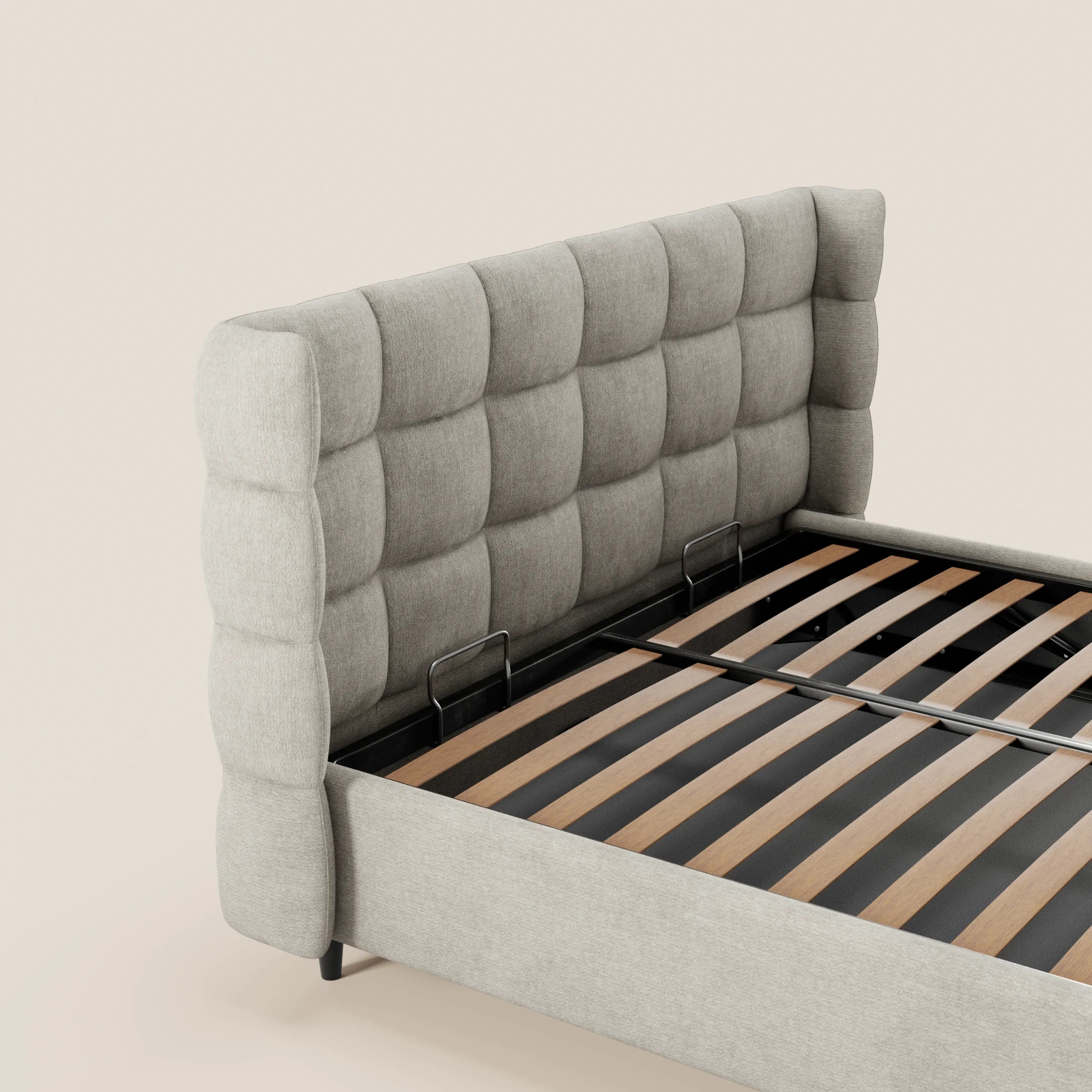Il letto imbottito RAGNAR di Letti.store presenta una testiera alta e morbida, con rivestimento capitonné avvolgente e profonde cuciture quadrate, doghe in legno a vista e un elegante tessuto certificato Oeko-Tex® in grigio chiaro, che risalta su uno sfondo beige.