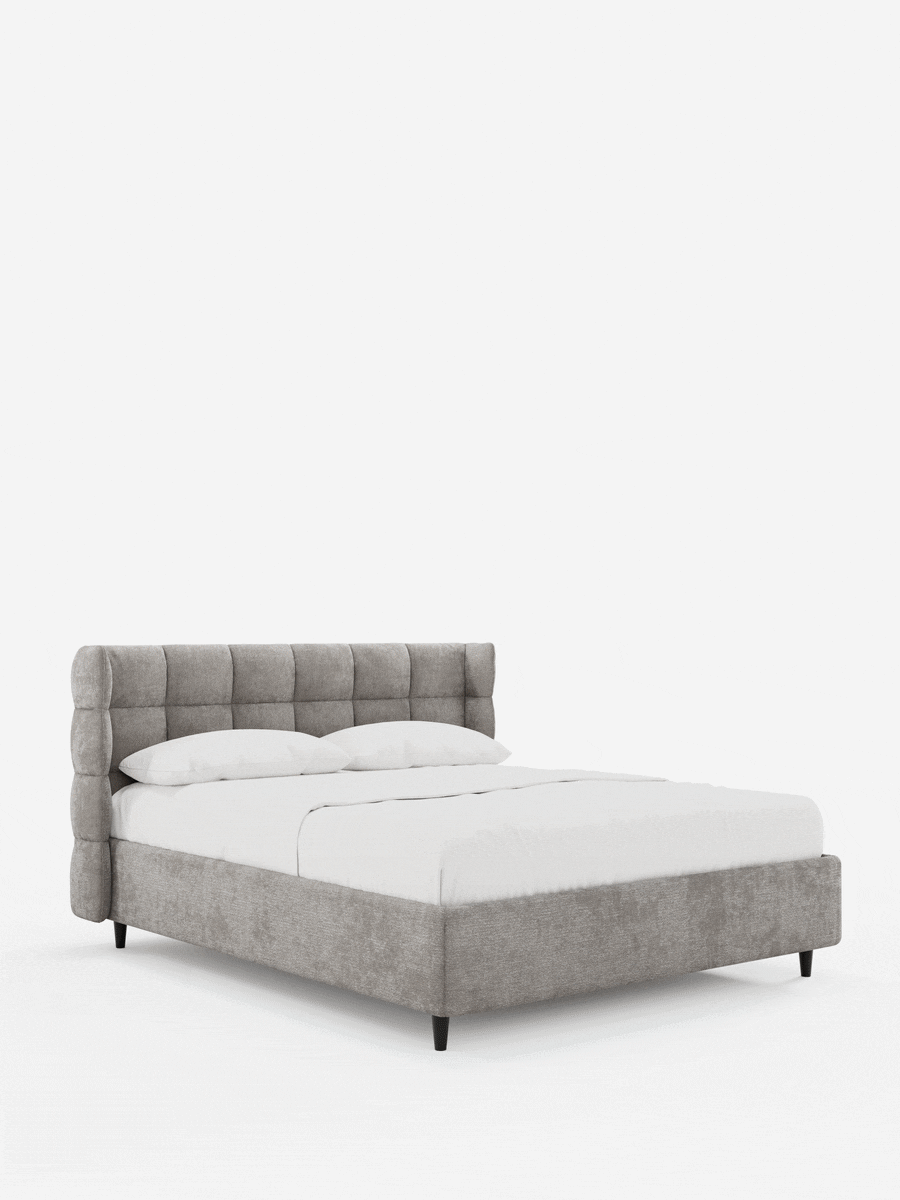 Un letto imbottito RAGNAR grigio con contenitore e testiera capitonné avvolgente, caratterizzata da un’alta testiera capitonné avvolgente, si staglia su uno sfondo bianco liscio, rivestito con lenzuola bianche immacolate e sostenuto da gambe corte e scure.
