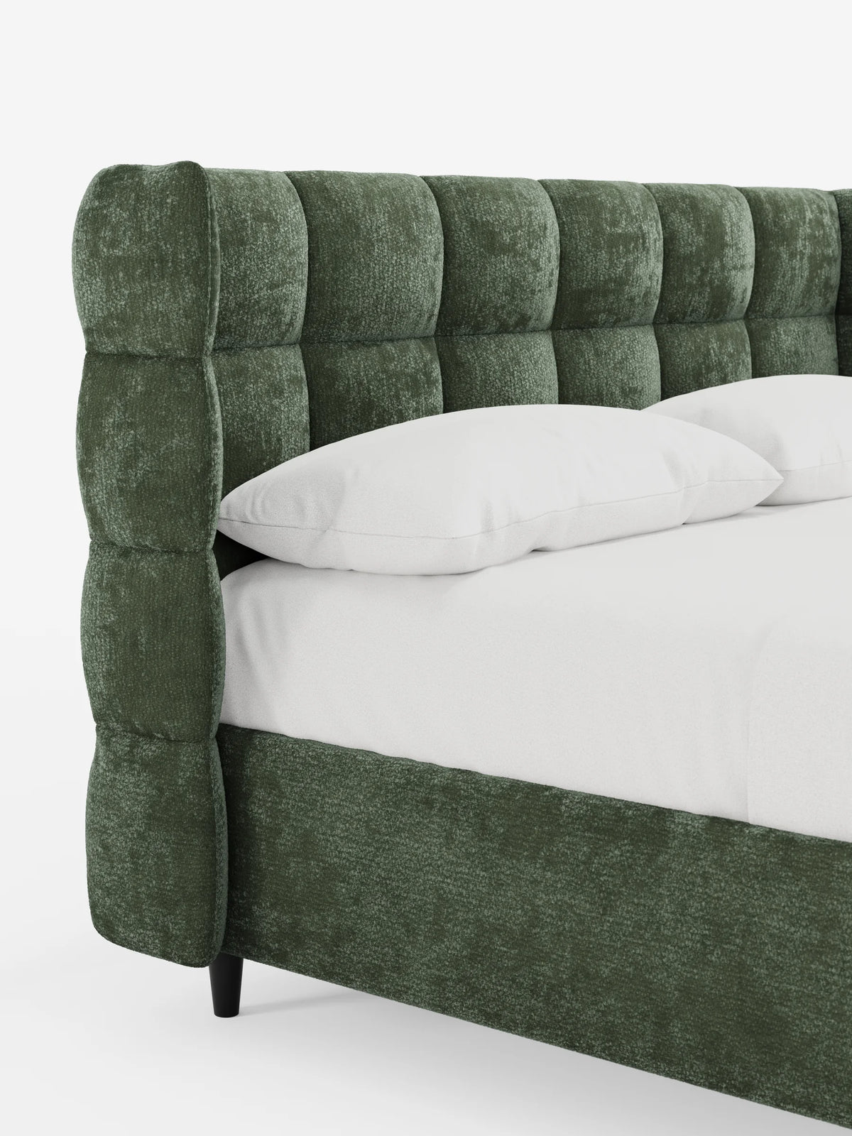 Il letto imbottito RAGNAR, dotato di contenitore e testiera capitonné avvolgente, presenta una testiera verde scuro capitonné che avvolge i lati, biancheria da letto bianca sul materasso e gambe corte e scure su uno sfondo bianco.