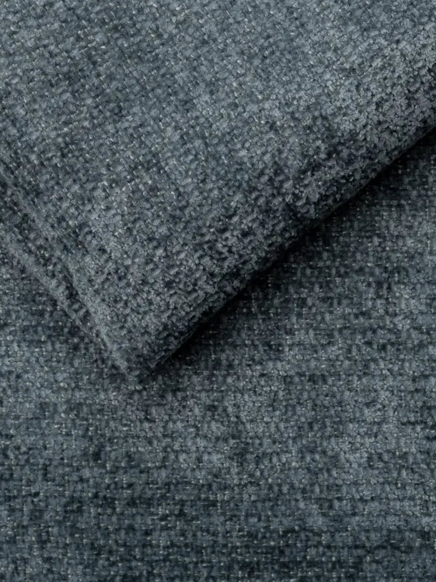 Un primo piano del tessuto grigio scuro a trama ruvida su un divano letto Ottaviano con letto estraibile – penisola reversibile e contenitore in tessuto materico smacchiabile, ripiegato per rivelare una trama fitta e nodosa nei toni del antracite e dell’ardesia.