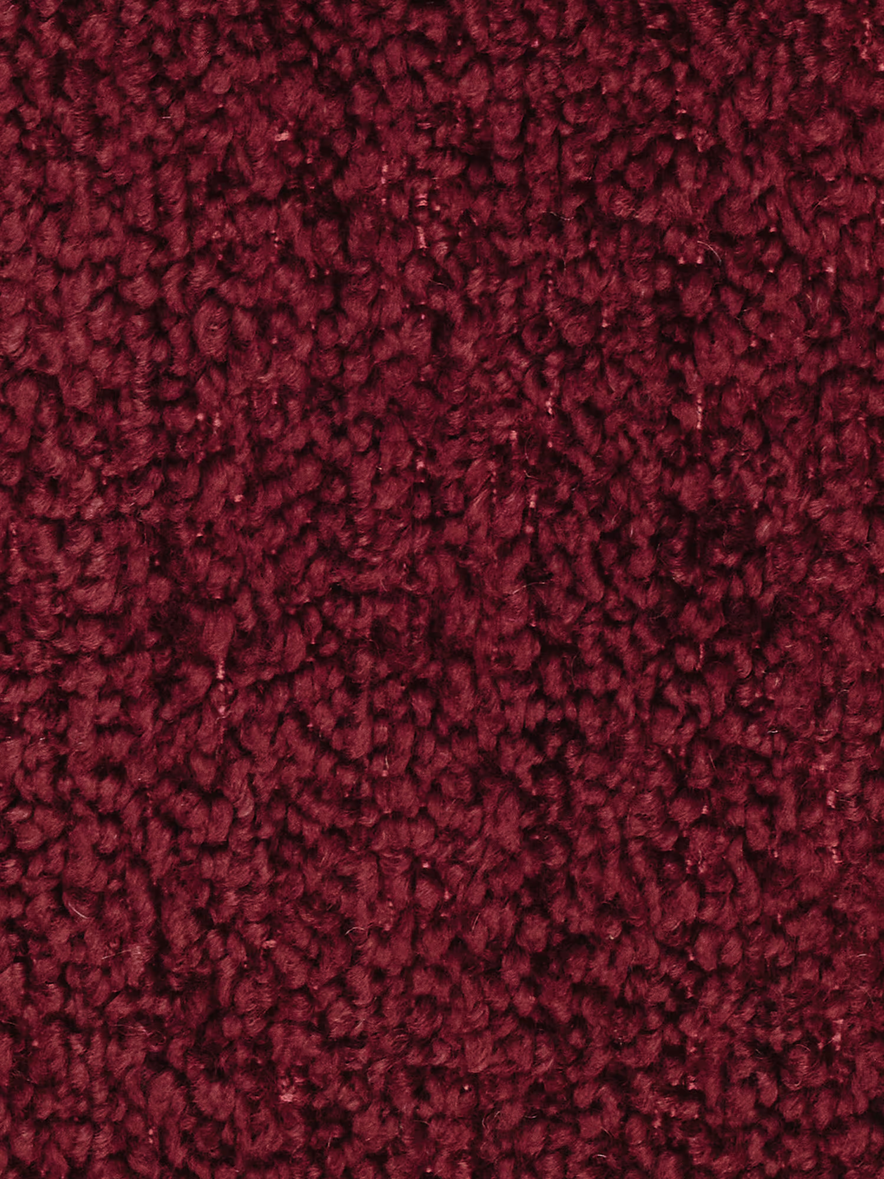 Primo piano del rivestimento in bouclé color bordeaux intenso e dalla trama rigata del divano angolare componibile e modulare Mosaic di Divani.Store. Il filato a riccioli e i dettagli capitonné creano una superficie densa e soffice, caratterizzata da sottili variazioni di tonalità, che esaltano il ricco fascino visivo del tessuto in diverse condizioni di illuminazione.