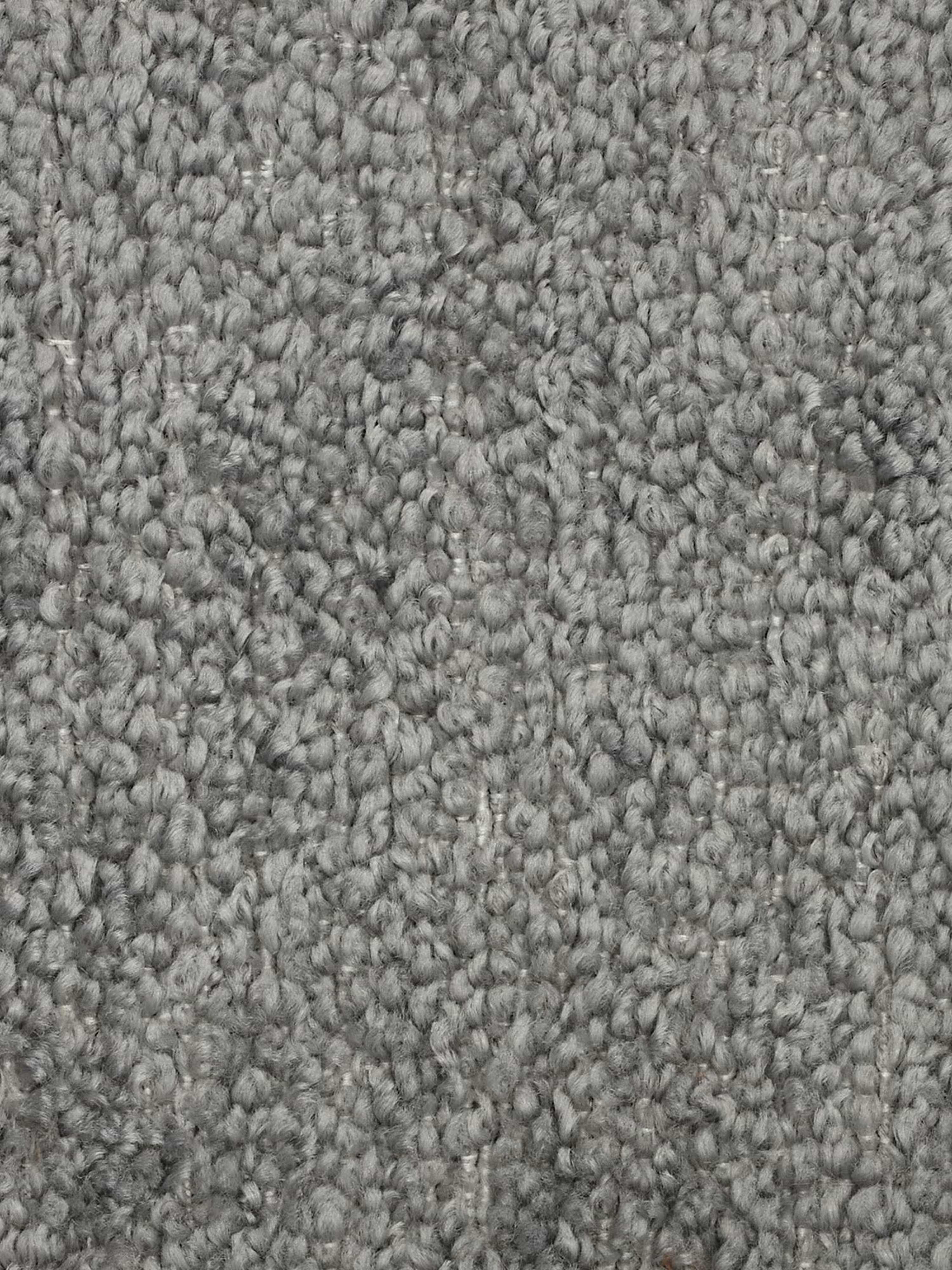 Primo piano di un tappeto a riccioli grigi, caratterizzato da fibre intrecciate a trama fitta e testurizzate in delicate sfumature di grigio che creano una superficie morbida e compatta dall’aspetto raffinato e screziato. I riccioli uniformi e fitti offrono un effetto morbido e imbottito, rendendolo la base ideale per un soggiorno moderno arredato con il divano angolare componibile e modulare Mosaic in bouclé: capitonné e design in tessuto smacchiabile T21 di Divani.Store.