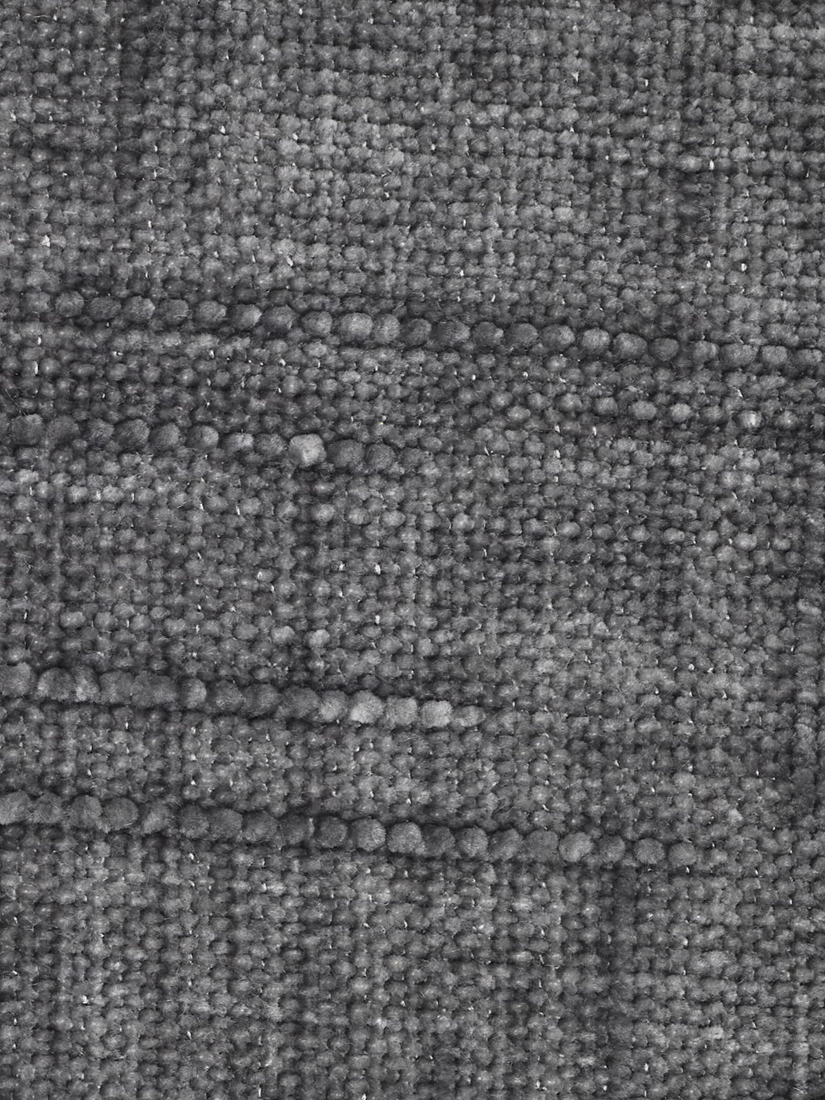 Primo piano del divano letto matrimoniale Pegaso con poggiatesta reclinabili in tessuto jacquard smacchiabile T22 di Divani.Store, caratterizzato da un tessuto jacquard grigio scuro dalla superficie ruvida e strutturata. Il tessuto presenta un caratteristico motivo a griglia composto da fili spessi e sottili, che conferisce al tessuto un aspetto tattile e leggermente irregolare. L’illuminazione mette in risalto la trama in rilievo del tessuto, esaltandone l’estetica moderna, perfetta per mobili