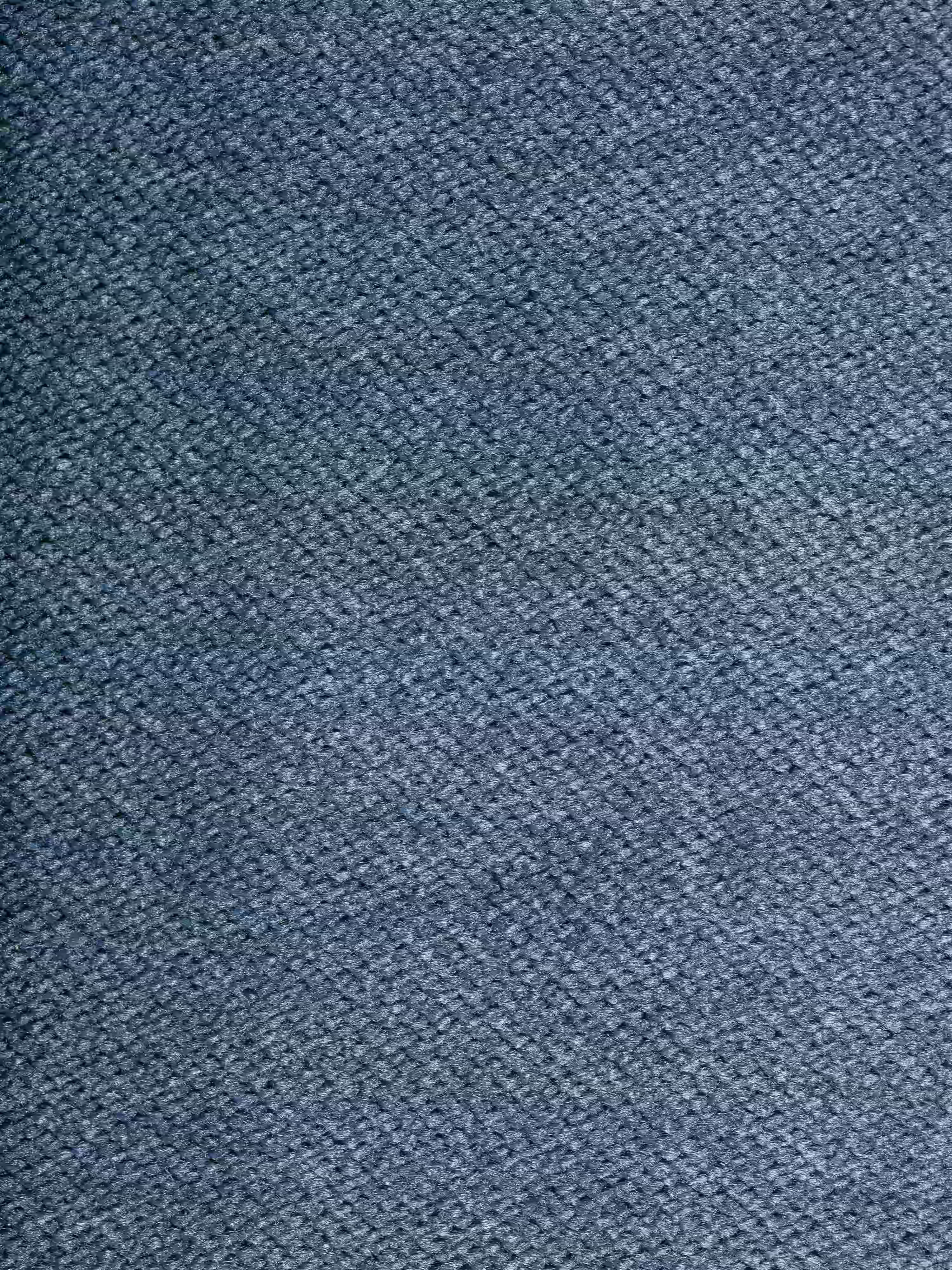 Un primo piano del raffinato tessuto T30 effetto velluto, resistente alle macchie, del divano angolare Michelangelo con penisola e sedute estensibili di Divani.Store, che presenta una fitta trama diagonale e diverse tonalità di blu che creano un aspetto delicatamente screziato e dalla consistenza morbida, tipico del suo design moderno a chaise longue. Nell’immagine non sono visibili oggetti né forme distinte.
