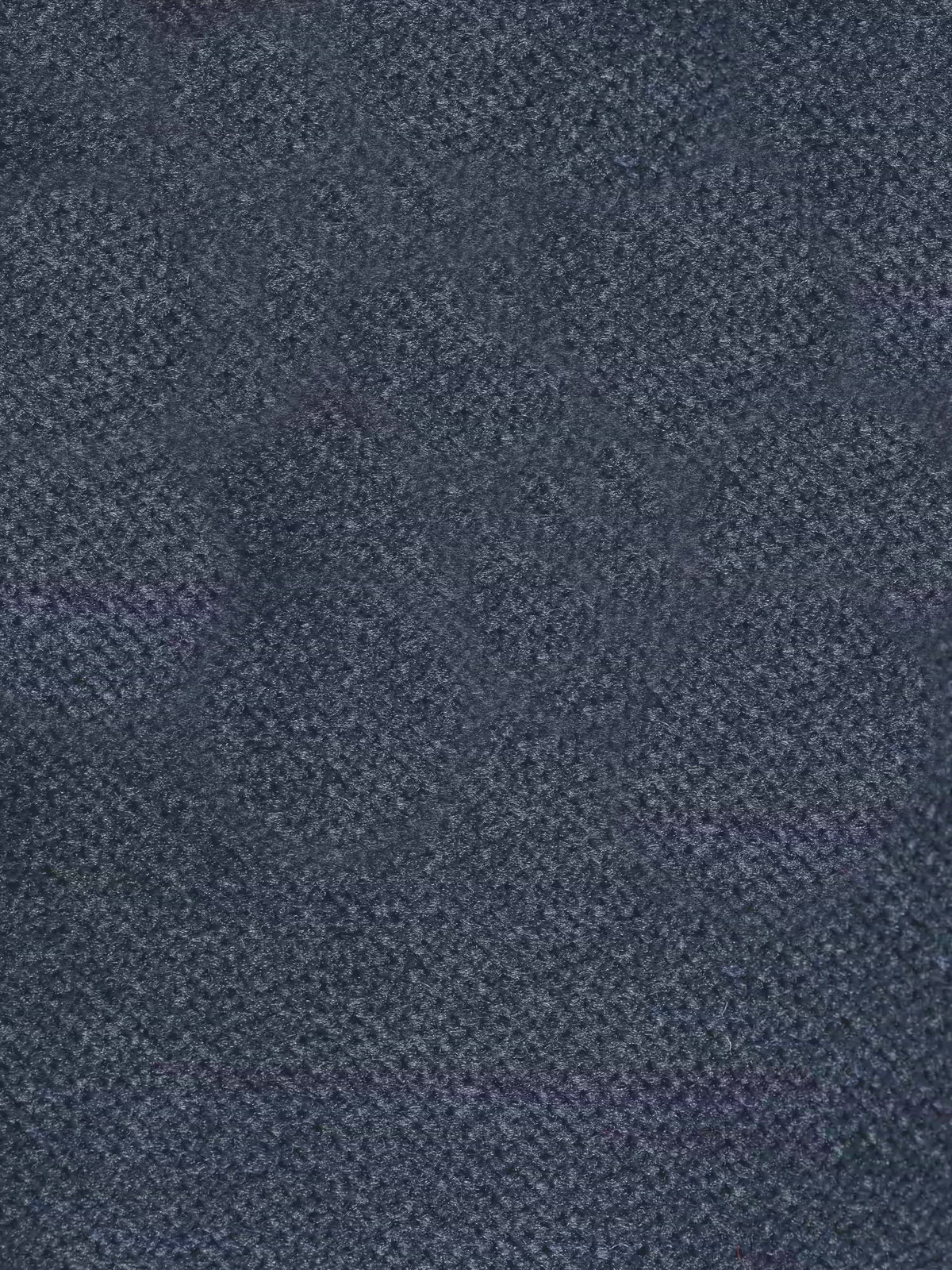 Primo piano di un tessuto scuro e strutturato, il “moderno tessuto vellutino smacchiabile T30”, del divano letto Dalia a 2, 3 e 4 posti con materasso H18 di Divani.Store. Il tessuto presenta un delicato motivo intrecciato nei toni del blu navy o del grigio antracite con un aspetto leggermente screziato, che suggerisce fibre fitte e morbide: un rivestimento perfetto da abbinare al comodo materasso da 18 cm. La superficie è priva di disegni o elementi visibili.