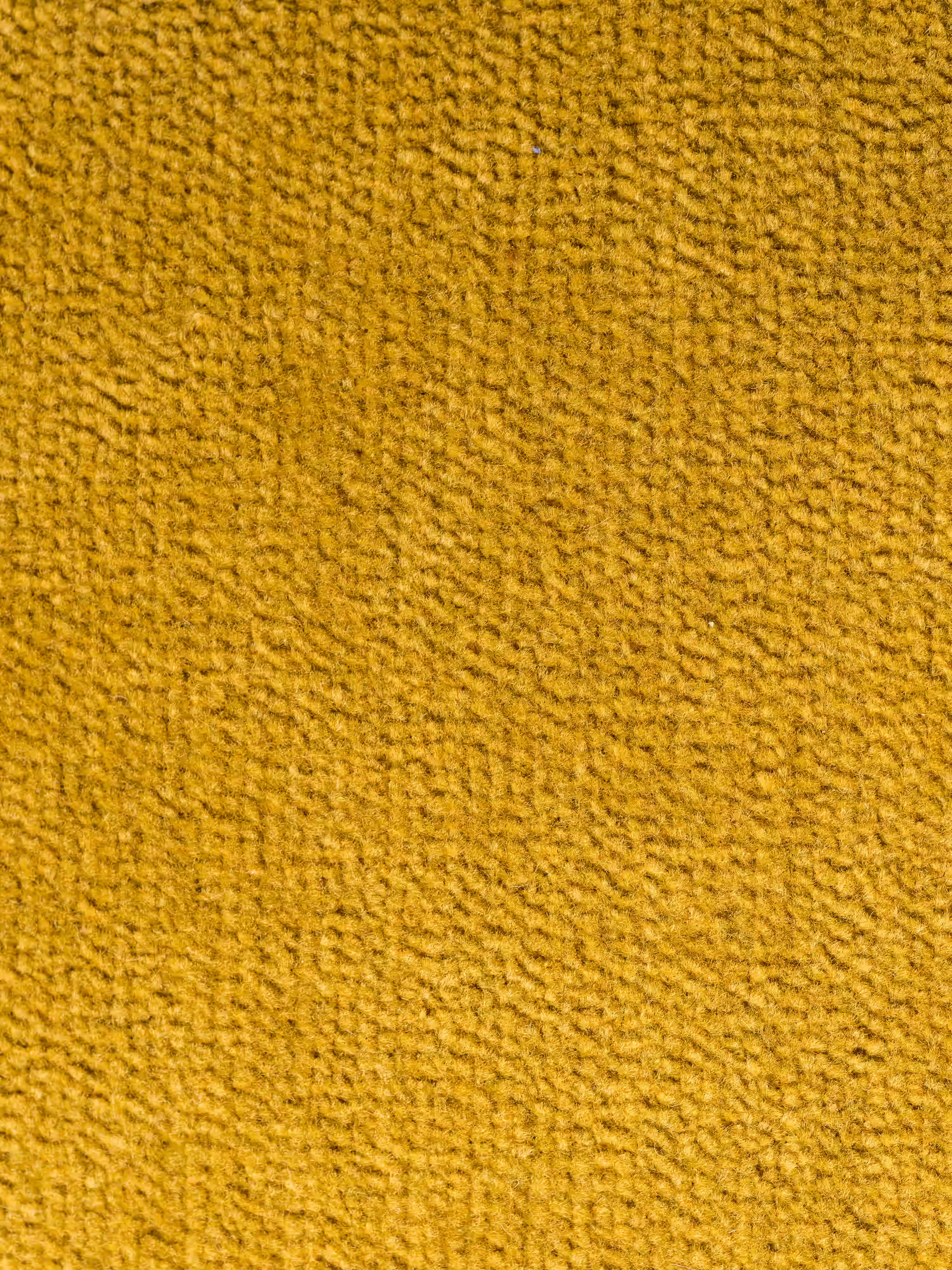 Primo piano sulla superficie testurizzata del tessuto giallo-arancio della poltrona letto Rift con materasso alto 22 cm e memory foam di Divani.L'immagine mostra fibre piccole e fitte e un motivo ondulato leggermente irregolare che conferisce una consistenza morbida e piacevole al tatto al rivestimento smacchiabile T31, perfetto per i modelli contemporanei di poltrone letto con schienale mobile. Nell'immagine non sono visibili altri oggetti o elementi.