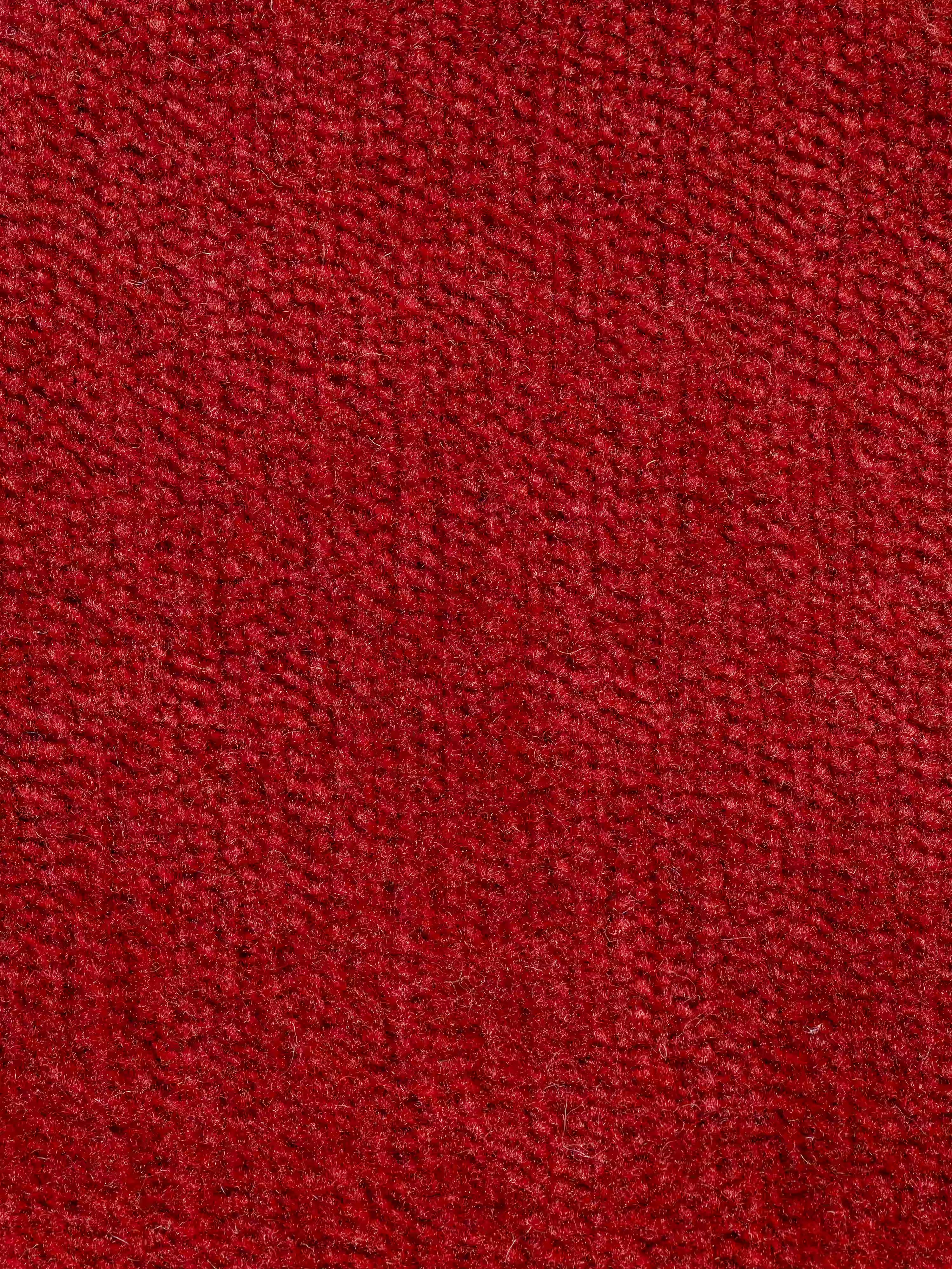 Primo piano del tessuto rosso smacchiabile T31 sulla poltrona letto Rift con materasso alto 22 cm e memory foam di Divani.Store, che ne evidenzia le fibre fitte e leggermente irregolari e la superficie morbida e soffice. Il tessuto, di colore rosso uniforme, presenta sottili variazioni di tonalità dovute alla direzione delle fibre, senza motivi visibili né colori aggiuntivi.