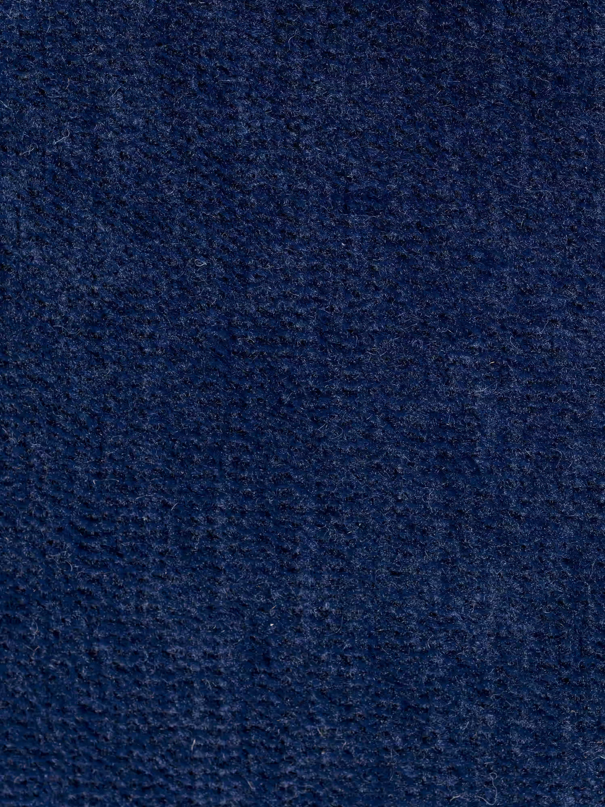 Primo piano del “tessuto morbido smacchiabile T31” blu scuro testurizzato di Divani.Store, che mette in risalto le sue fibre finemente intrecciate e le sottili variazioni di colore. La superficie presenta una consistenza morbida e vellutata con linee verticali e orizzontali visibili, rendendolo una scelta ideale per il rivestimento del divano angolare Monarch con penisola e relax elettrico per l’allungamento delle sedute con poggiatesta reclinabili.