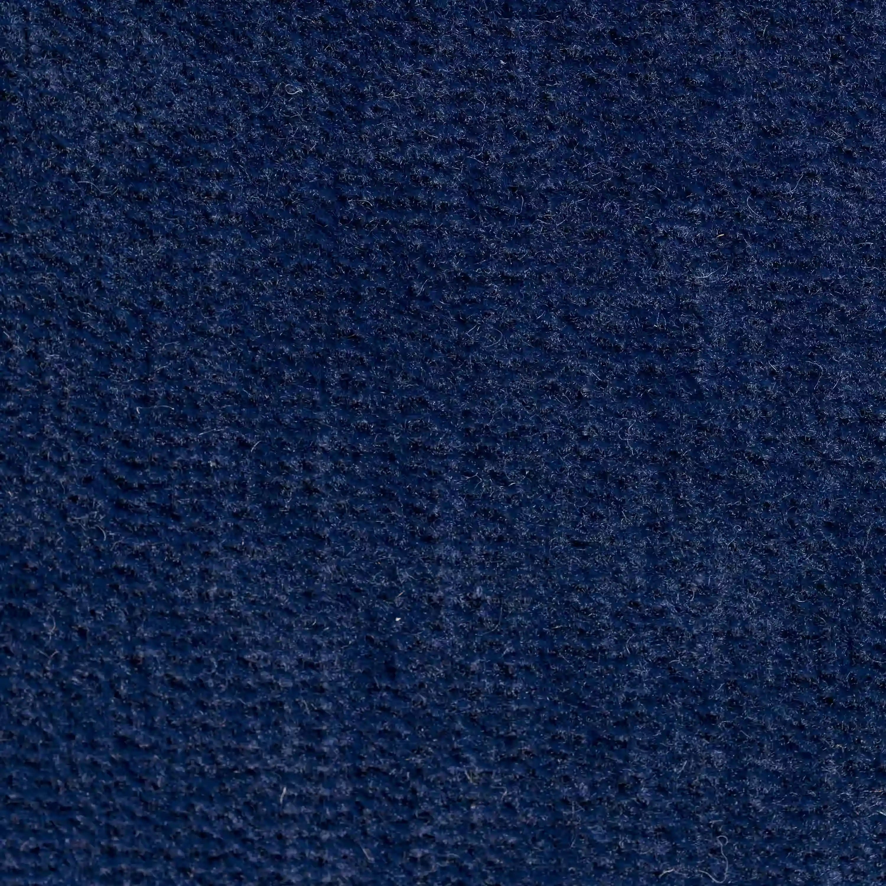Primo piano del cuscino Bolero di Divani.Store in tessuto T31 blu scuro, caratterizzato da una superficie morbida e strutturata con sottili creste. Il materiale smacchiabile, impermeabile e irrestringibile offre colori ricchi e sottili variazioni di sfumature.