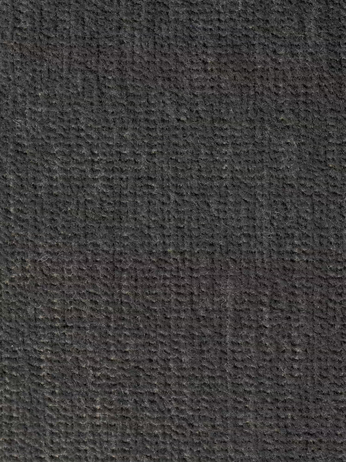 Primo piano della superficie strutturata, di colore grigio scuro, del divano Monarch con relax elettrico per l’allungamento delle sedute e poggiatesta reclinabile, realizzato in morbido tessuto smacchiabile T31 di Divani.Store. Il delicato motivo intrecciato e le fibre a vista evocano un rivestimento raffinato, con lievi variazioni cromatiche che conferiscono un aspetto naturale e leggermente ruvido. L'illuminazione accentua la profondità e la dimensione di questo elegante tessuto.