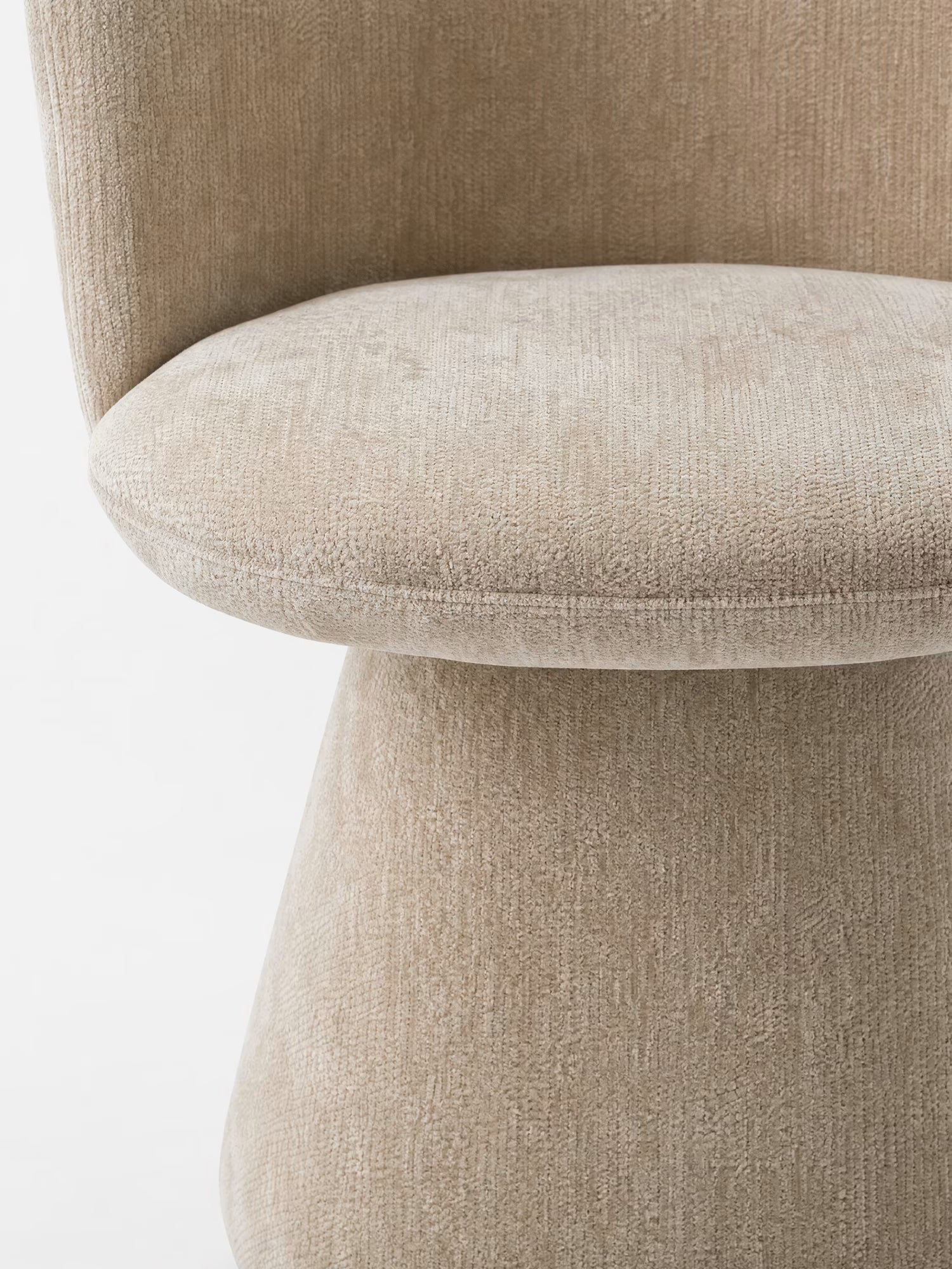 Primo piano della sedia moderna Talia di Divani.Store, rivestita in morbida ciniglia beige certificata OEKO-TEX®. Lo schienale curvo, la seduta arrotondata e la base avvolgente e lineare creano un look moderno e armonioso, senza gambe a vista.