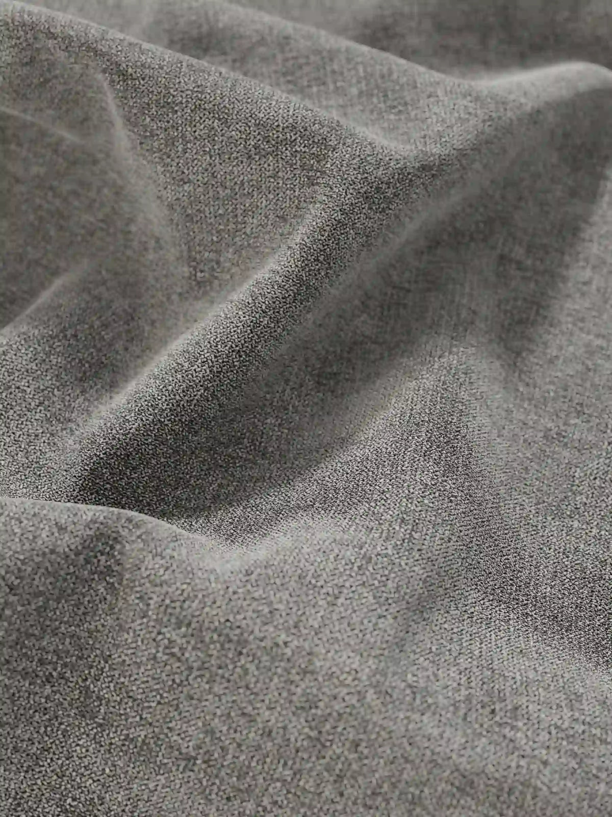 Primo piano del letto sommier imbottito ERON, di colore grigio, realizzato in tessuto intrecciato con vano contenitore in tessuto impermeabile certificato Oeko-Tex, caratterizzato da pieghe profonde e naturali, una trama a grana fine, una finitura opaca e morbide ombre all’interno delle pieghe.