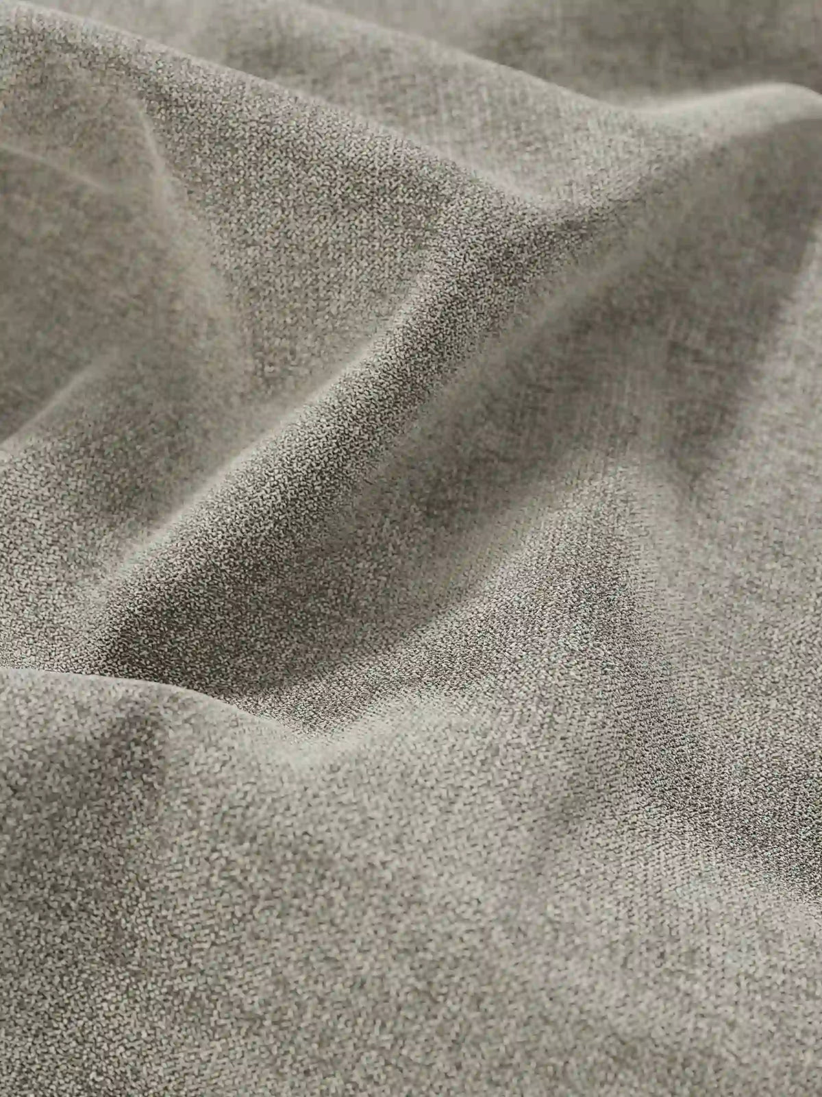 Primo piano sul tessuto beige a trama fine, con morbide pieghe e giochi di ombra, di un letto sommier imbottito ERON con vano contenitore in tessuto impermeabile certificato Oeko-Tex, caratterizzato da una trama neutra e piacevole al tatto.