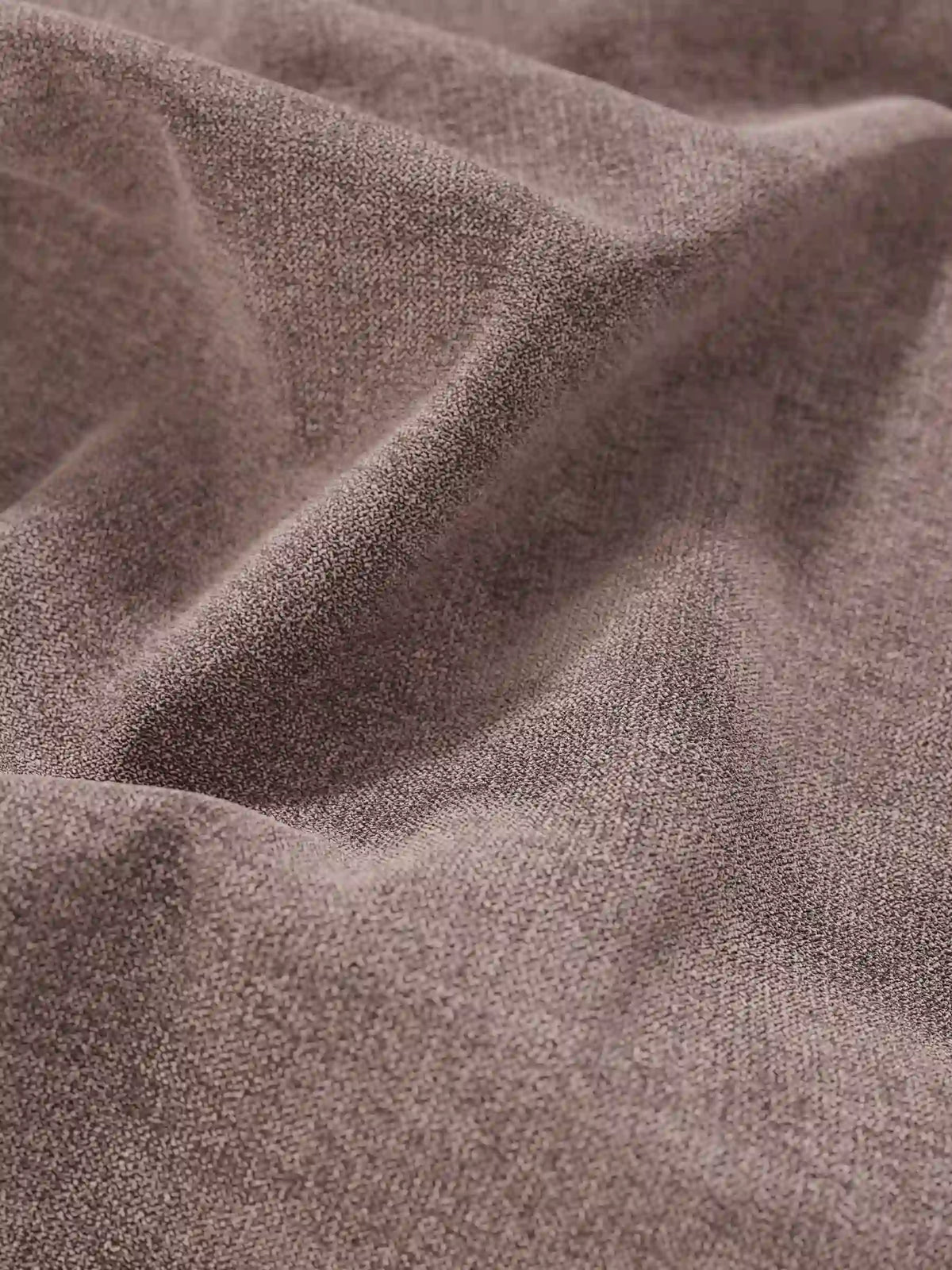 Un primo piano del tessuto color taupe che riveste il letto sommier imbottito ERON con vano contenitore in tessuto impermeabile certificato Oeko-Tex, caratterizzato da pieghe diagonali in rilievo e da raffinati dettagli intrecciati che creano sottili variazioni di luce e ombra.