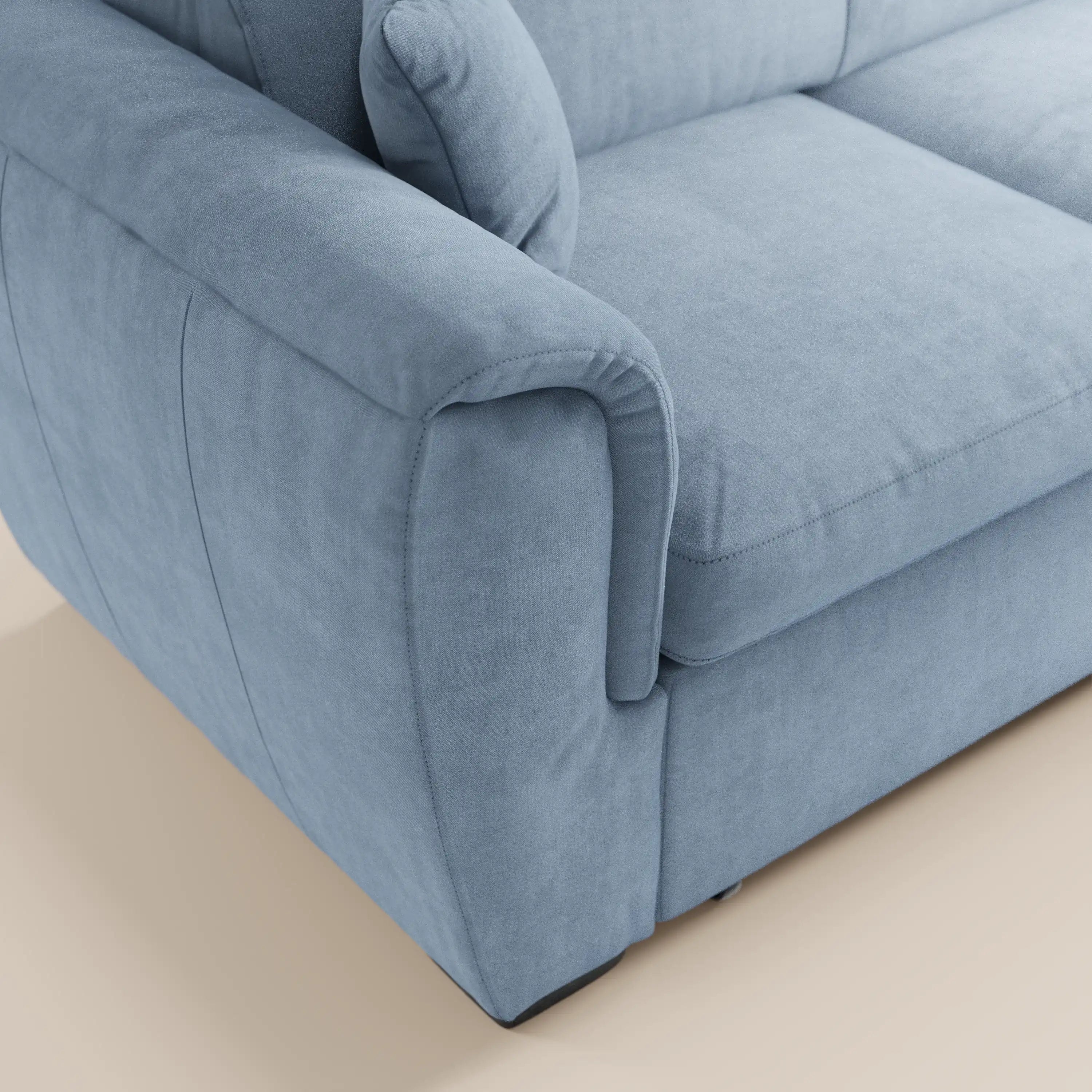 Primo piano del divano angolare reversibile Titano di Divani.Store in azzurro, dotato di poggiatesta reclinabili, braccioli imbottiti e cuscino di seduta. Include un cuscino coordinato e un pouf contenitore, rivestiti in tessuto antimacchia certificato Oeko-Tex®.