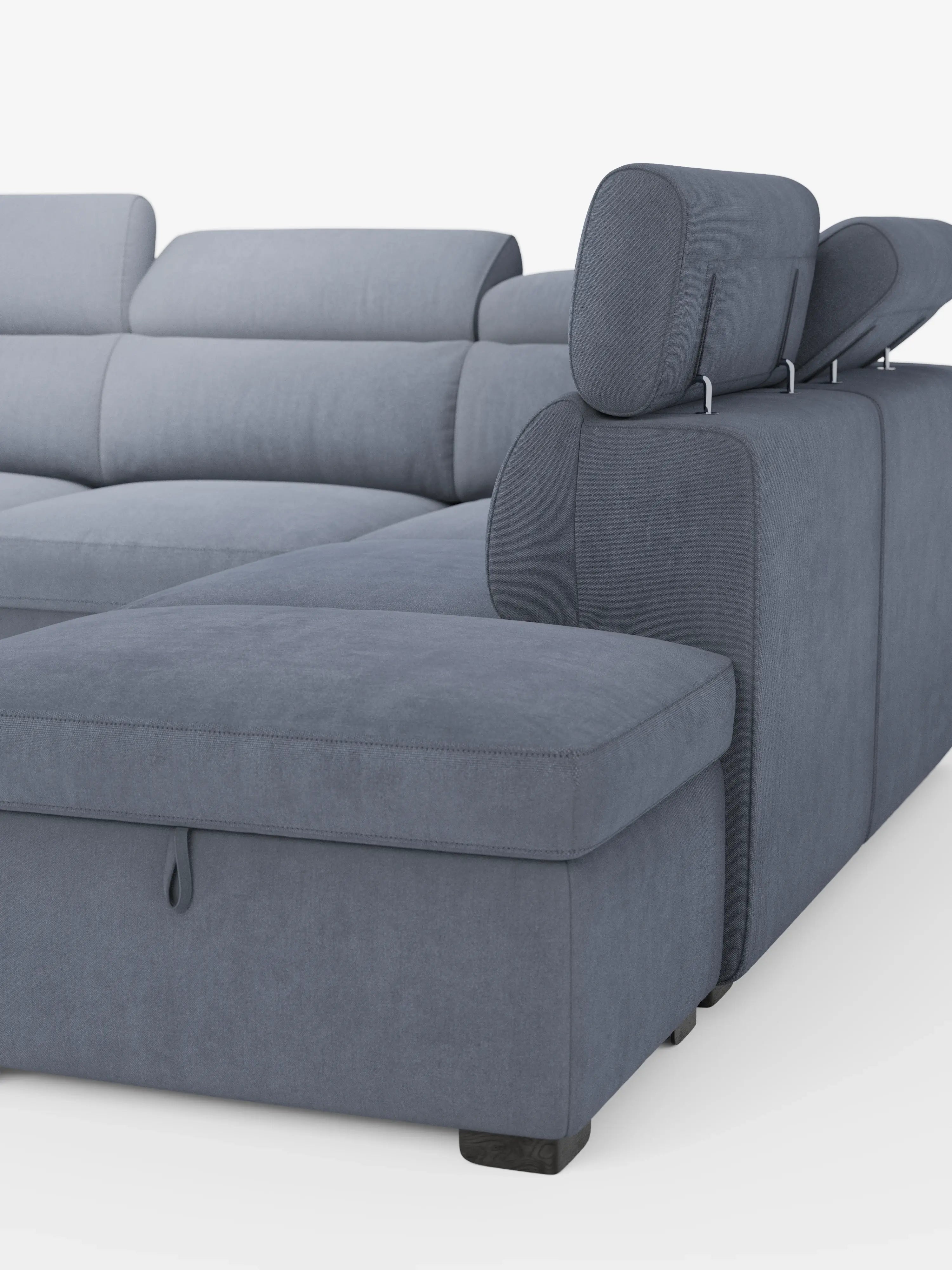 Un moderno divano angolare reversibile Titano di Divani.Store, rivestito in tessuto Smacchiabile Oeko-Tex® grigio-blu, dotato di poggiatesta regolabili, una sezione estensibile e un pouf contenitore. Il design minimalista comprende morbidi cuscini con cuciture a vista, il tutto su uno sfondo bianco a tinta unita che mette in risalto i dettagli del divano.