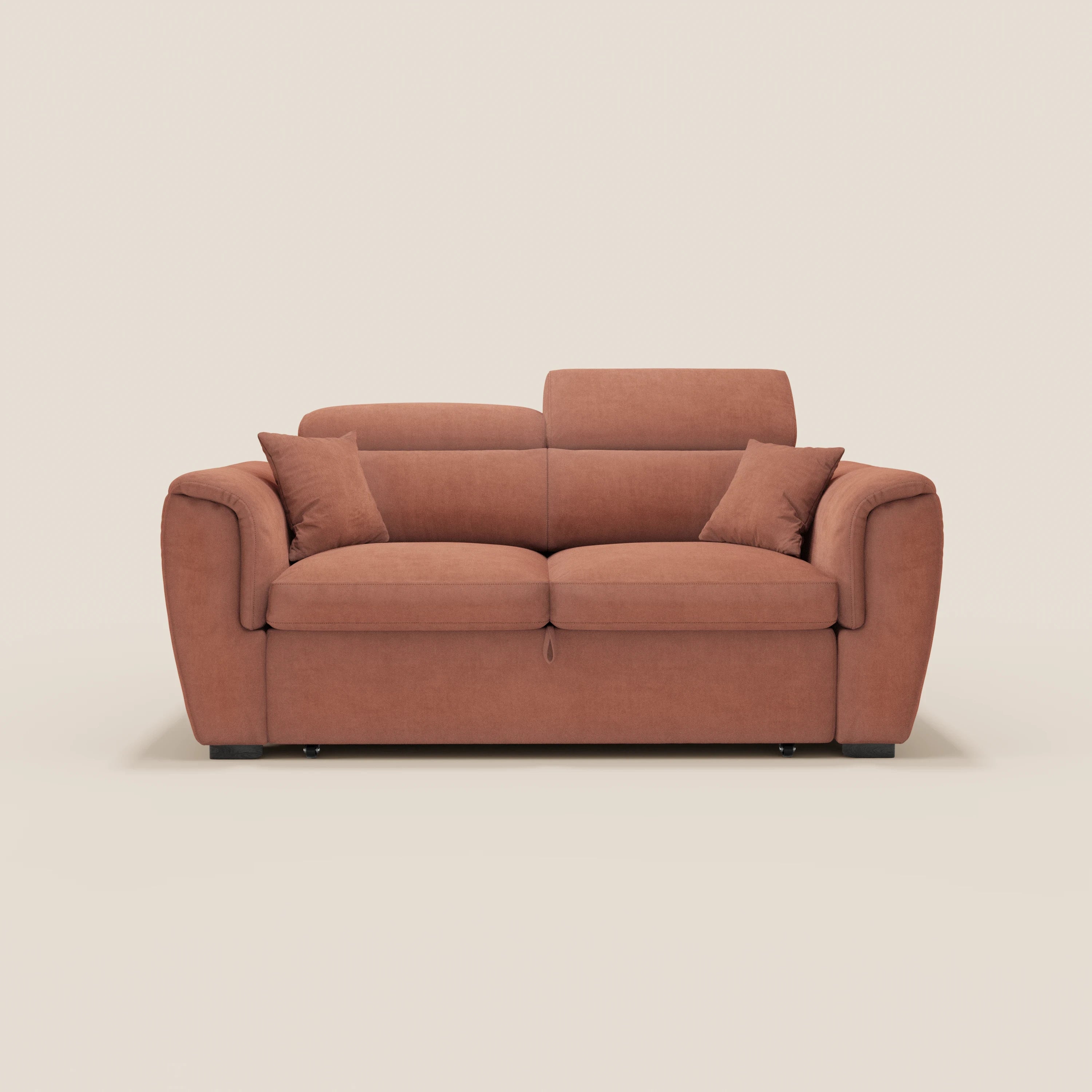 Un moderno divano a due posti estraibile Titano color ruggine di Divani.Store, dotato di due cuscini di seduta, schienali abbinati, braccioli imbottiti, quattro cuscini quadrati e poggiatesta regolabili, rivestito in tessuto antimacchia certificato Oeko-Tex® su fondo bianco sporco.