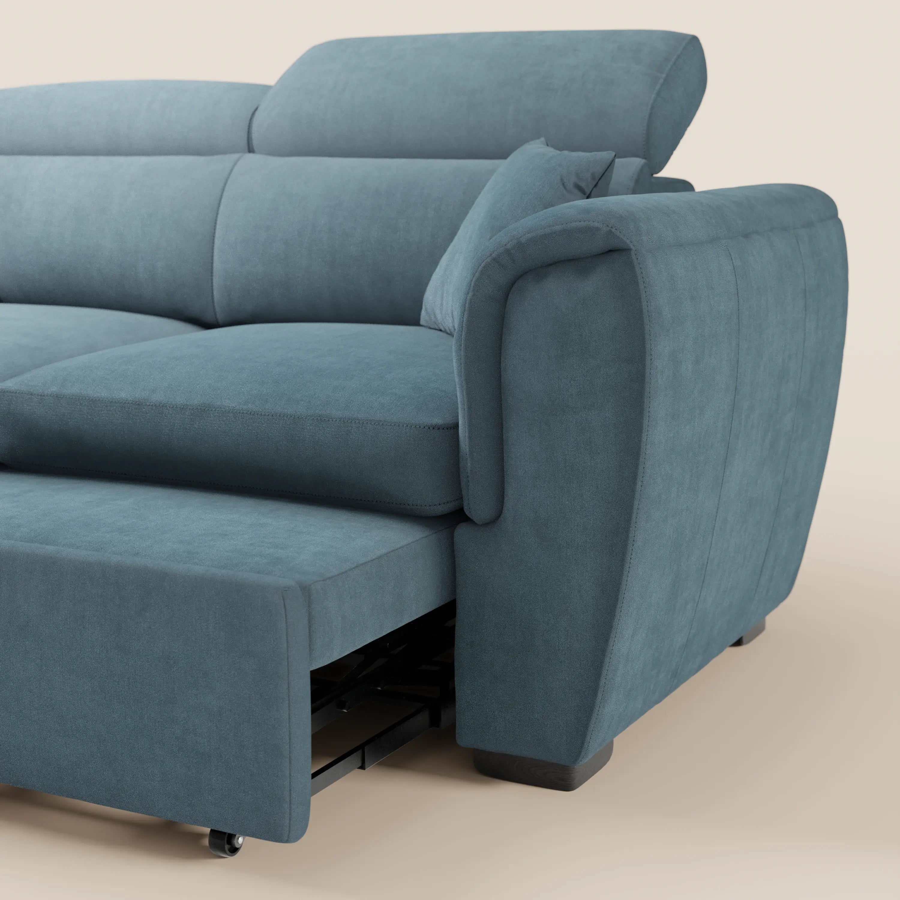 Un primo piano del divano a 2 posti estraibile Titano di Divani.Store, realizzato in tessuto blu Oeko-Tex® antimacchia. Presenta morbidi cuscini, ampi braccioli imbottiti, letto estraibile su rotelle e poggiatesta reclinabili su uno sfondo chiaro.