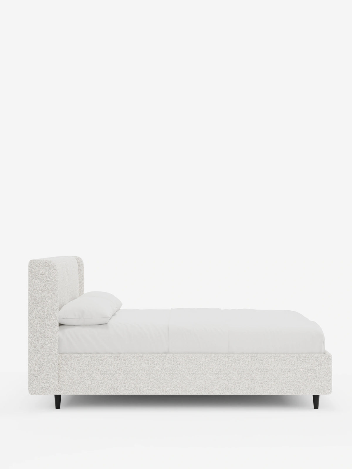 Il letto VALKIRIA presenta un design moderno e imbottito, caratterizzato da una testiera alta e avvolgente, un tessuto chiaro dalla trama ruvida, un unico cuscino e gambe corte, affusolate e di colore scuro, raffigurate di profilo su uno sfondo bianco.
