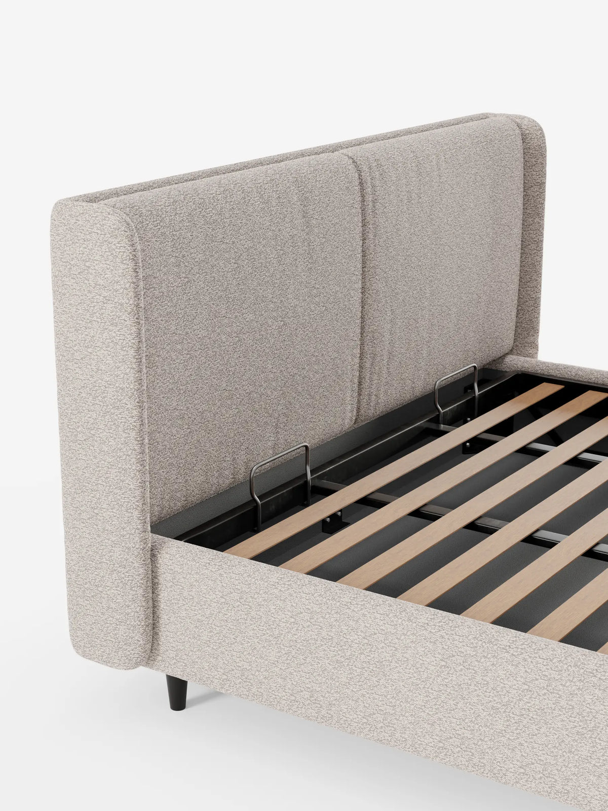 VALKIRIA, letto di design con contenitore e testiera avvolgente, caratterizzato da un’alta testiera avvolgente in tessuto beige e da una struttura rialzata che lascia intravedere una base a doghe in legno con barre di sostegno in metallo su uno sfondo a tinta unita.