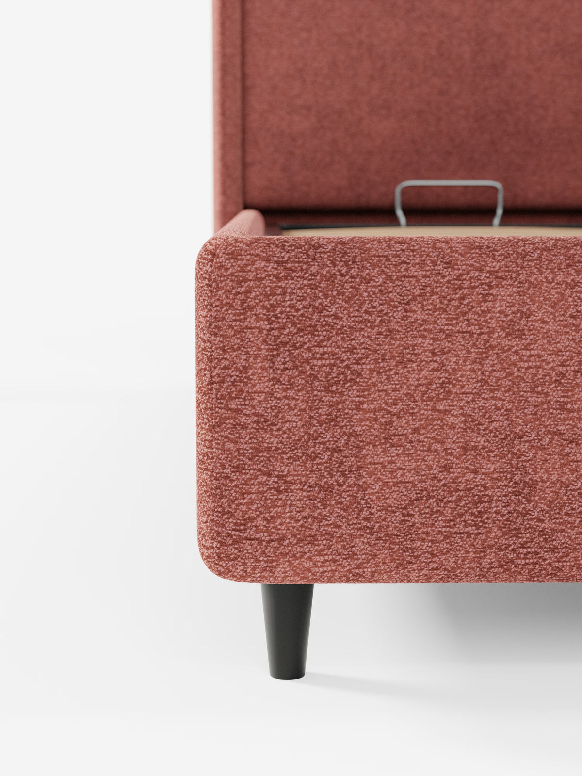 Primo piano del letto di design VALKIRIA con vano contenitore e testiera avvolgente di Letti.store, un letto rettangolare imbottito di colore rosa con gambe affusolate nere. L’angolo visibile ne sottolinea il raffinato design contemporaneo, mentre una leggera fessura nella parte superiore ne suggerisce la funzione pratica di letto contenitore. Sullo sfondo bianco a tinta unita, risaltano la trama e il colore del tessuto certificato Oeko-Tex® e dei due cuscini imbottiti.