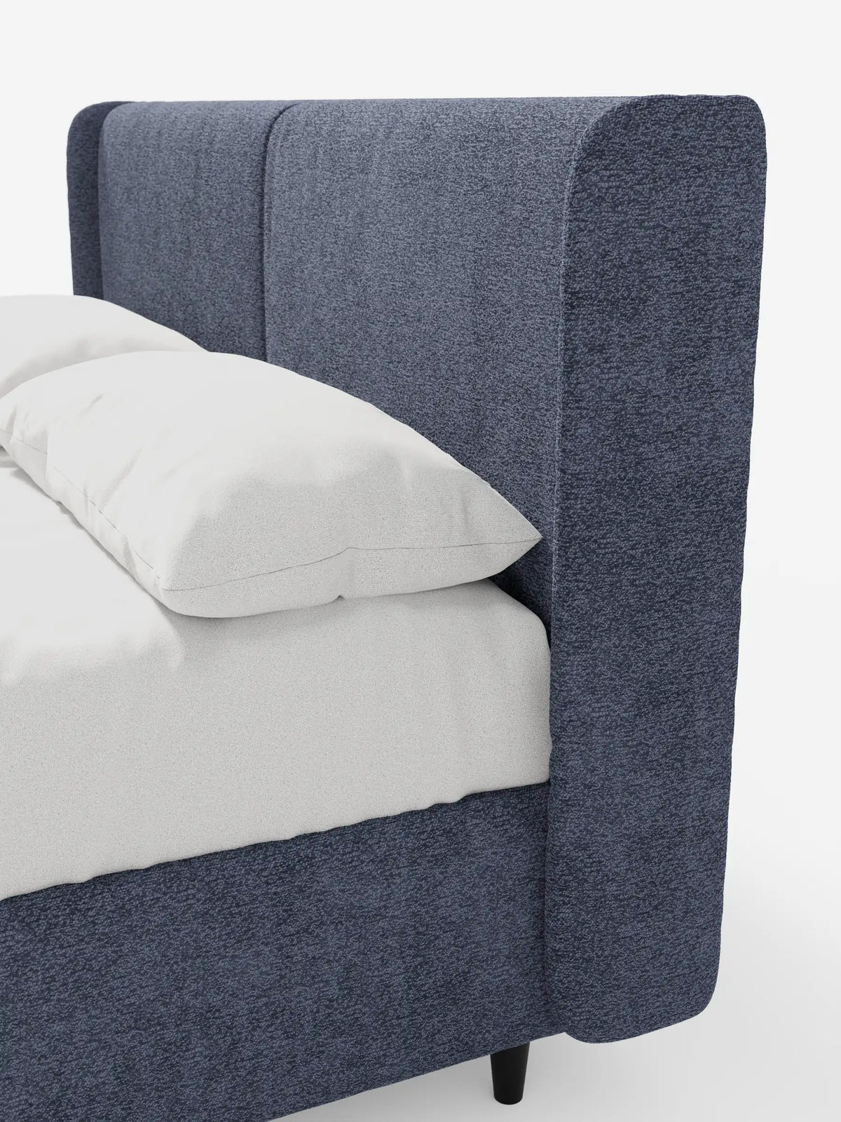 VALKIRIA, letto di design con contenitore e testiera avvolgente, presenta una testiera alta e ricurva rivestita in tessuto blu scuro testurizzato, con due cuscini rettangolari bianchi sul lenzuolo coordinato, sostenuta da gambe corte e cilindriche di colore scuro.