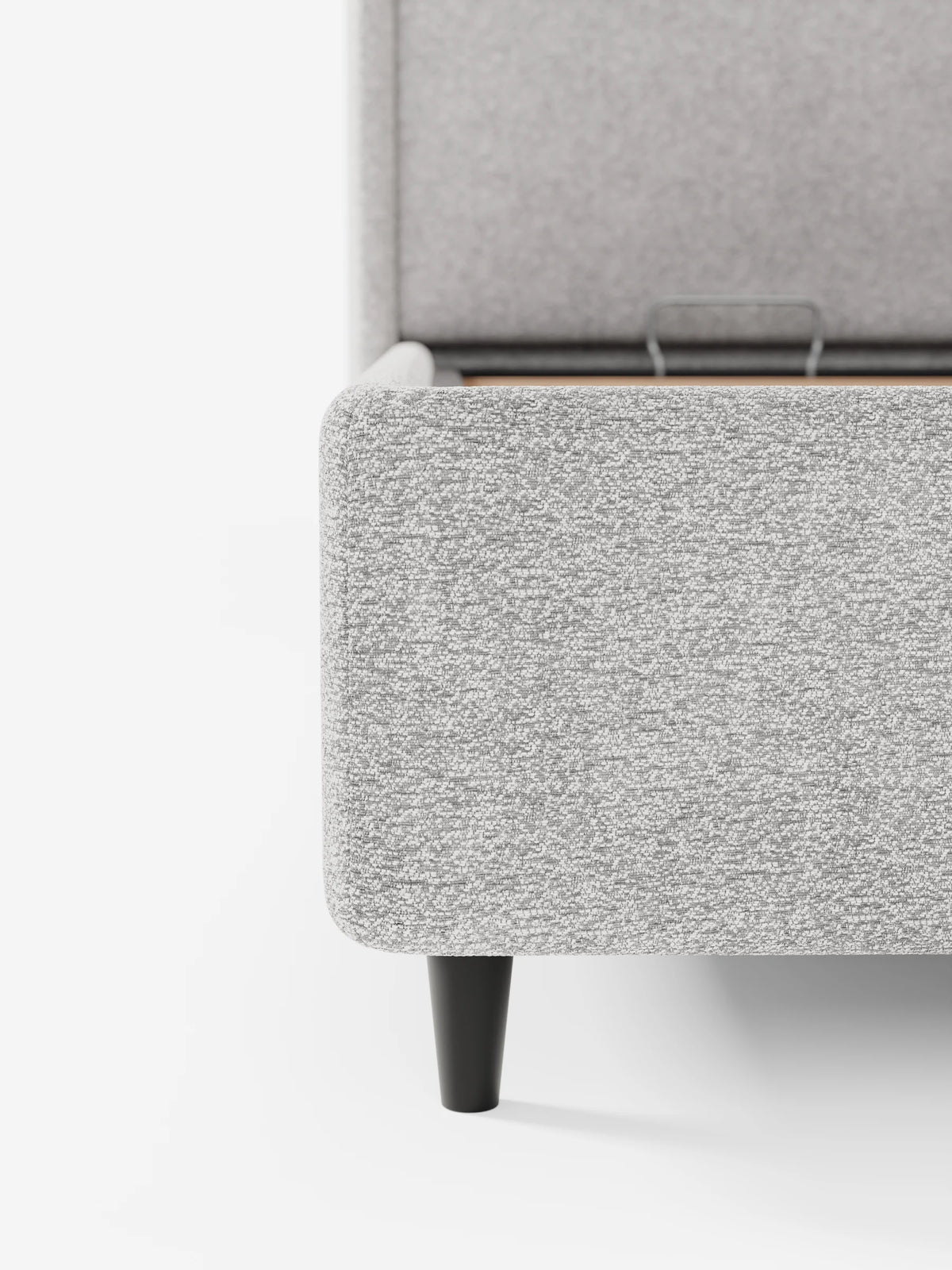 Un primo piano di un letto di design VALKIRIA con vano contenitore e testiera avvolgente in tessuto testurizzato grigio chiaro, che mostra una maniglia in metallo su una struttura con gambe nere in contrasto con una testiera imbottita in stile contemporaneo.