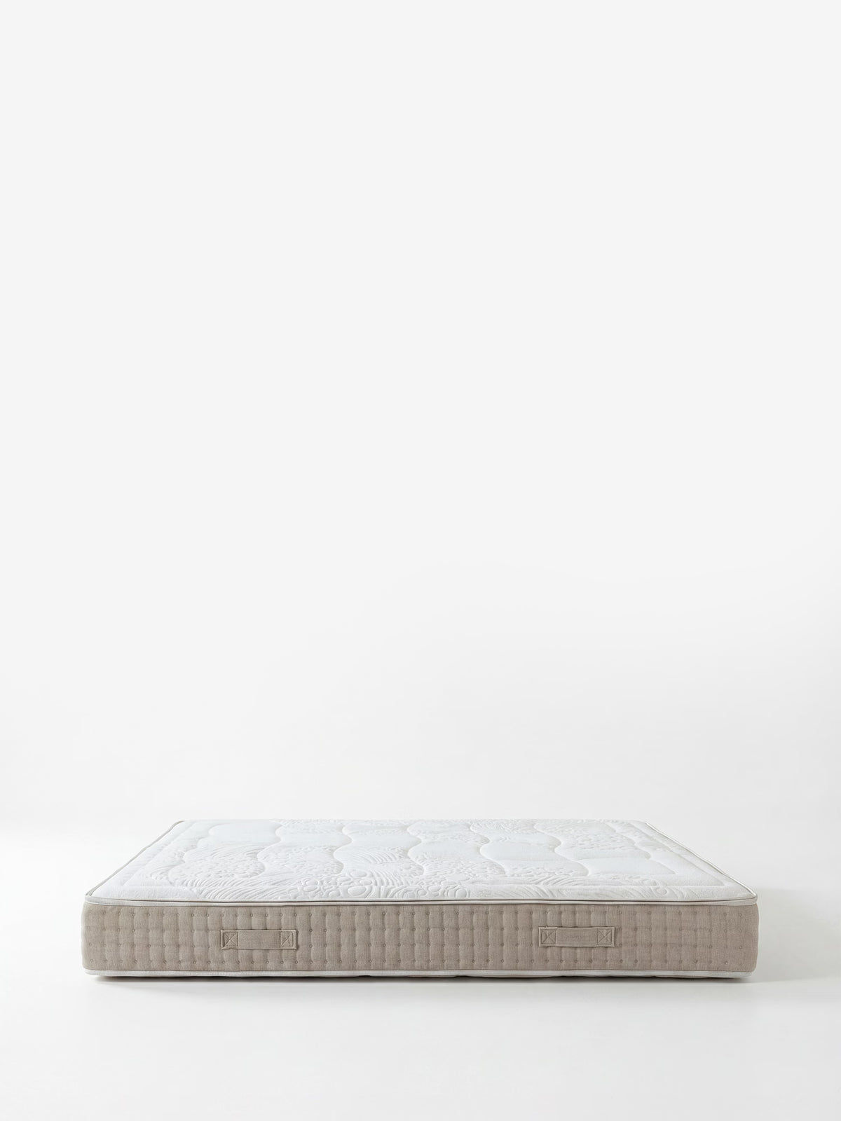 Un materasso Divani.Store VELTHA – Materasso Bio-Adattivo con molle insacchettate e lattice naturale a 7 zone, color beige, è ripreso su uno sfondo bianco liscio, con la parte superiore bianca trapuntata. I lati, dalla trama intrecciata, presentano due manici in tessuto. L’immagine minimalista è ben illuminata, senza altri oggetti in campo.