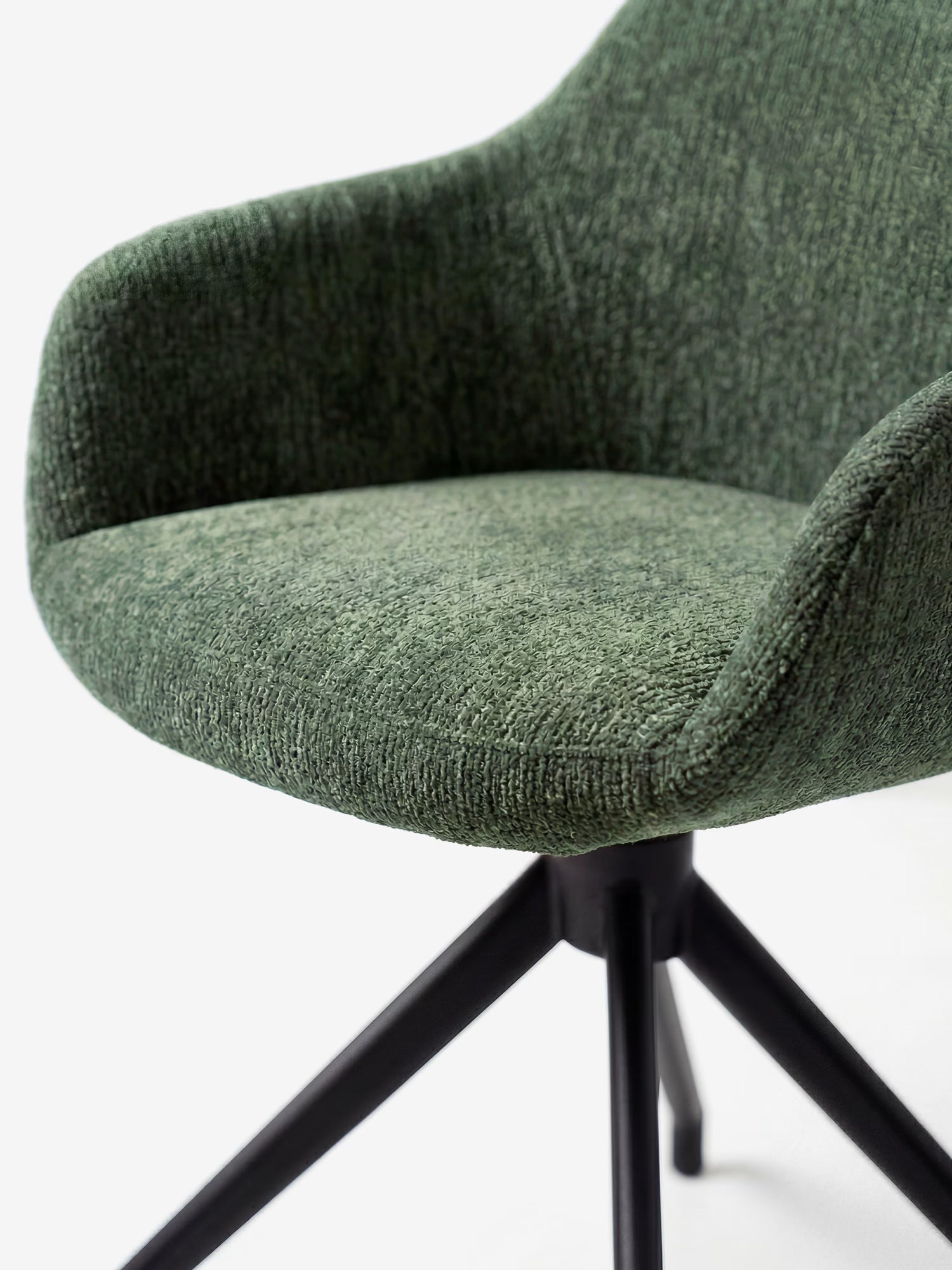 Primo piano della sedia imbottita Vico di Divani.Store, rivestita in tessuto morbido al tatto certificato OEKO-TEX®, con un moderno schienale curvo di colore verde e gambe in metallo nero che si allargano verso l'esterno. Presentata su uno sfondo bianco a tinta unita.